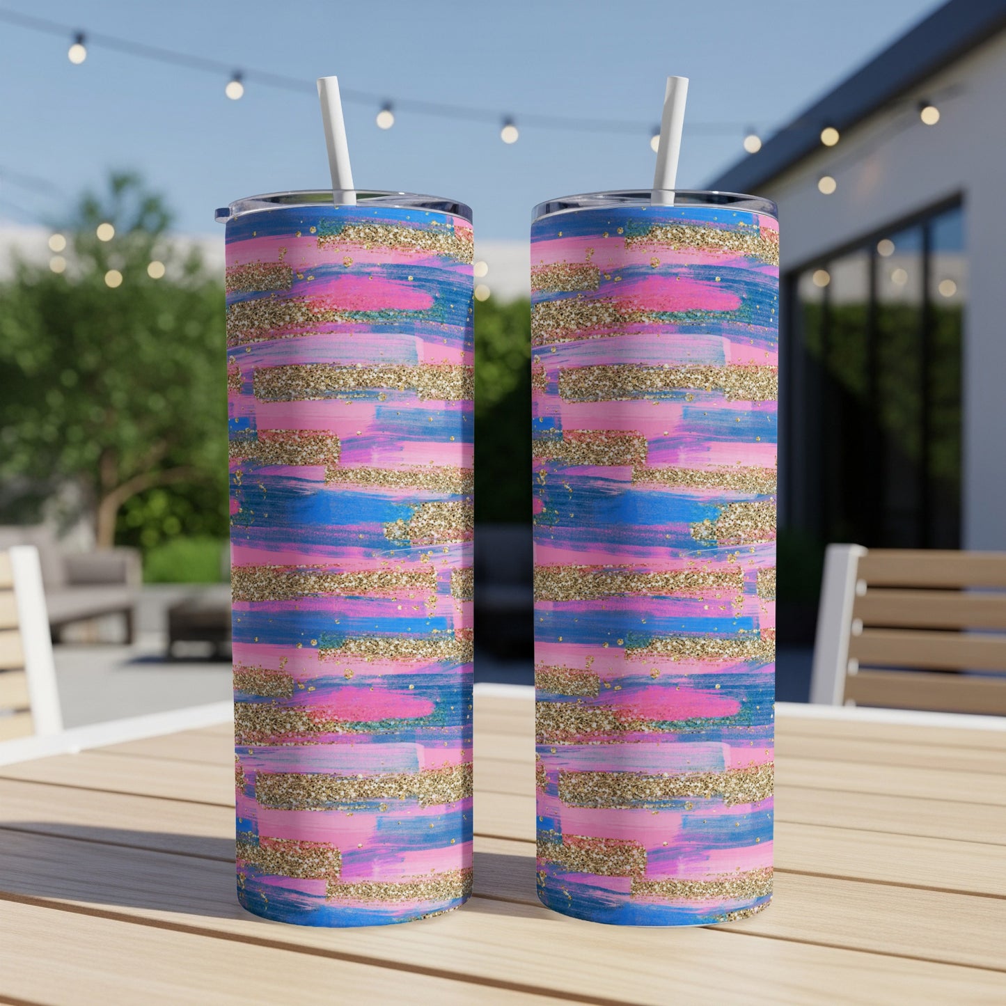 Two tumblers with pink, blue, and gold brushstroke design on a table.
