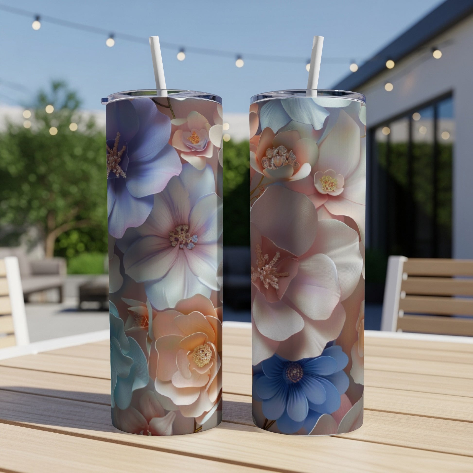 Two tumblers with pastel floral designs sit on a wooden table outdoors.