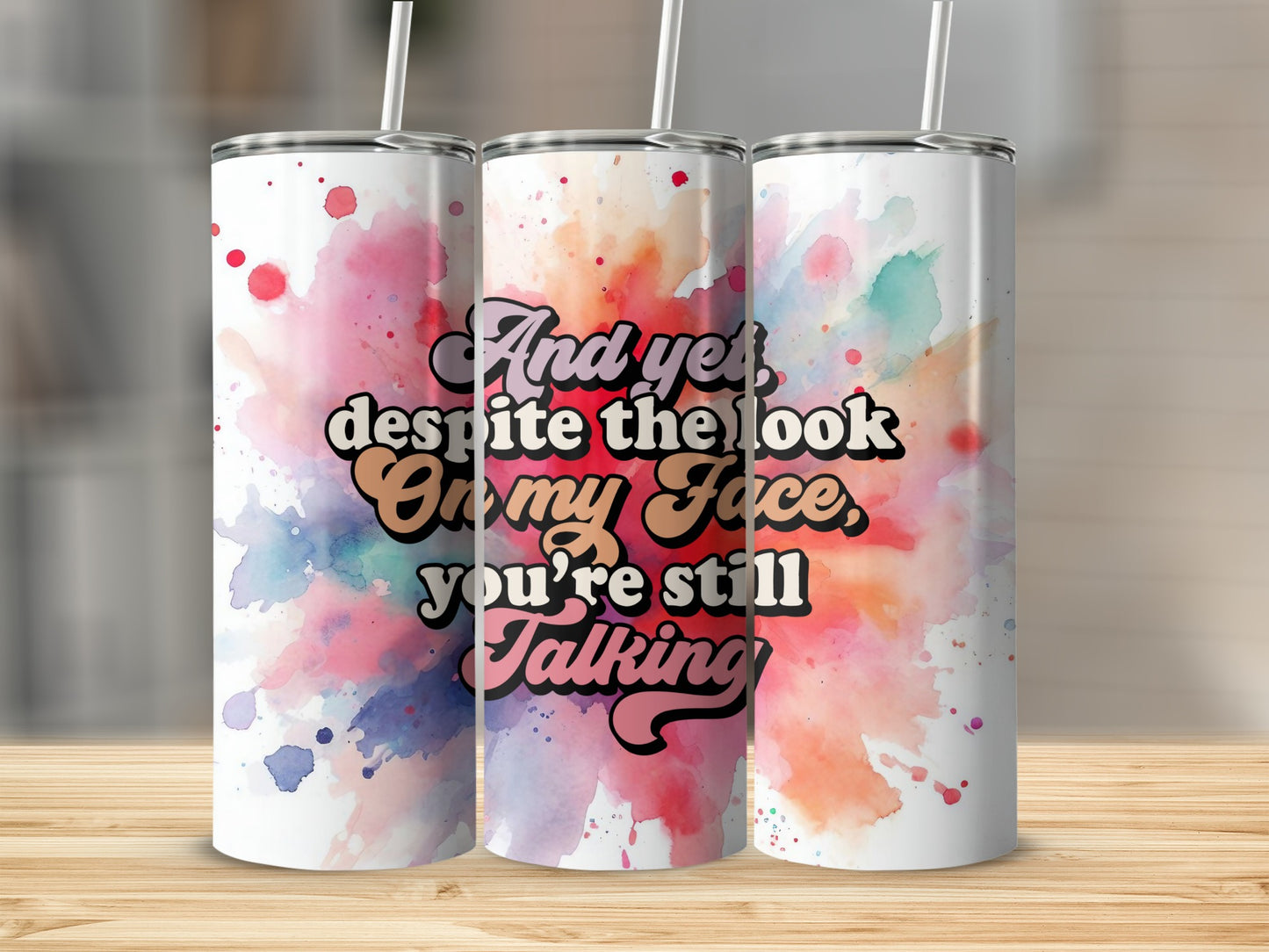 Tumbler with "And yet despite the look on my face you're still talking" text on watercolor background.