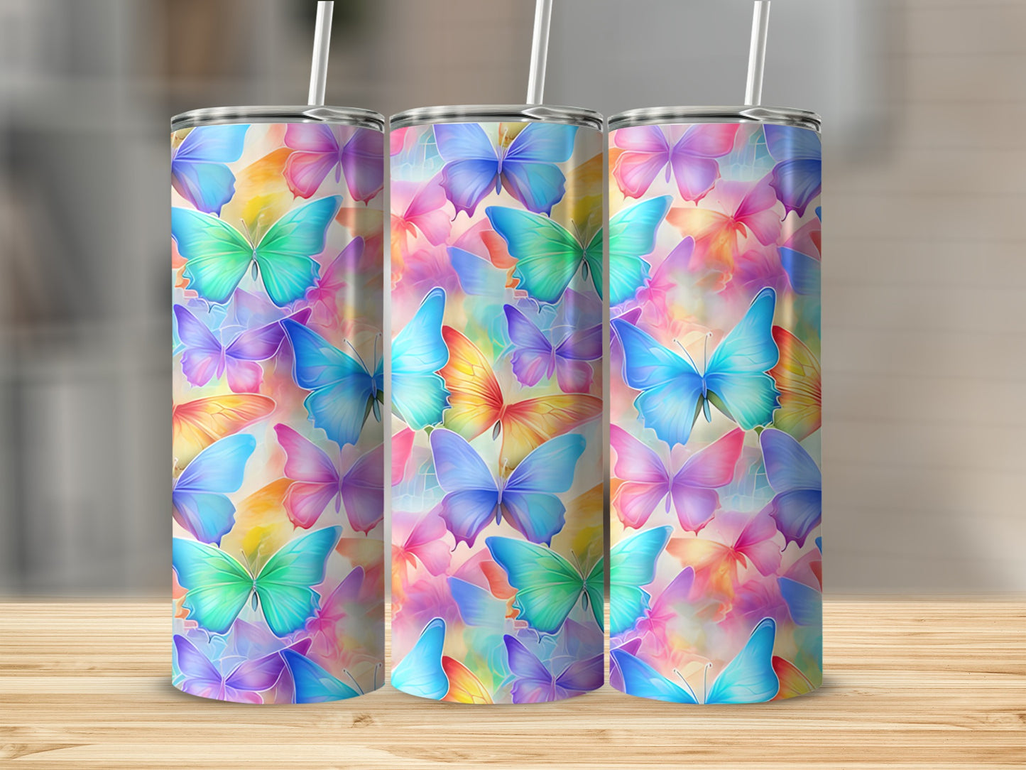 Three tumblers with colorful butterfly patterns on a wooden surface.