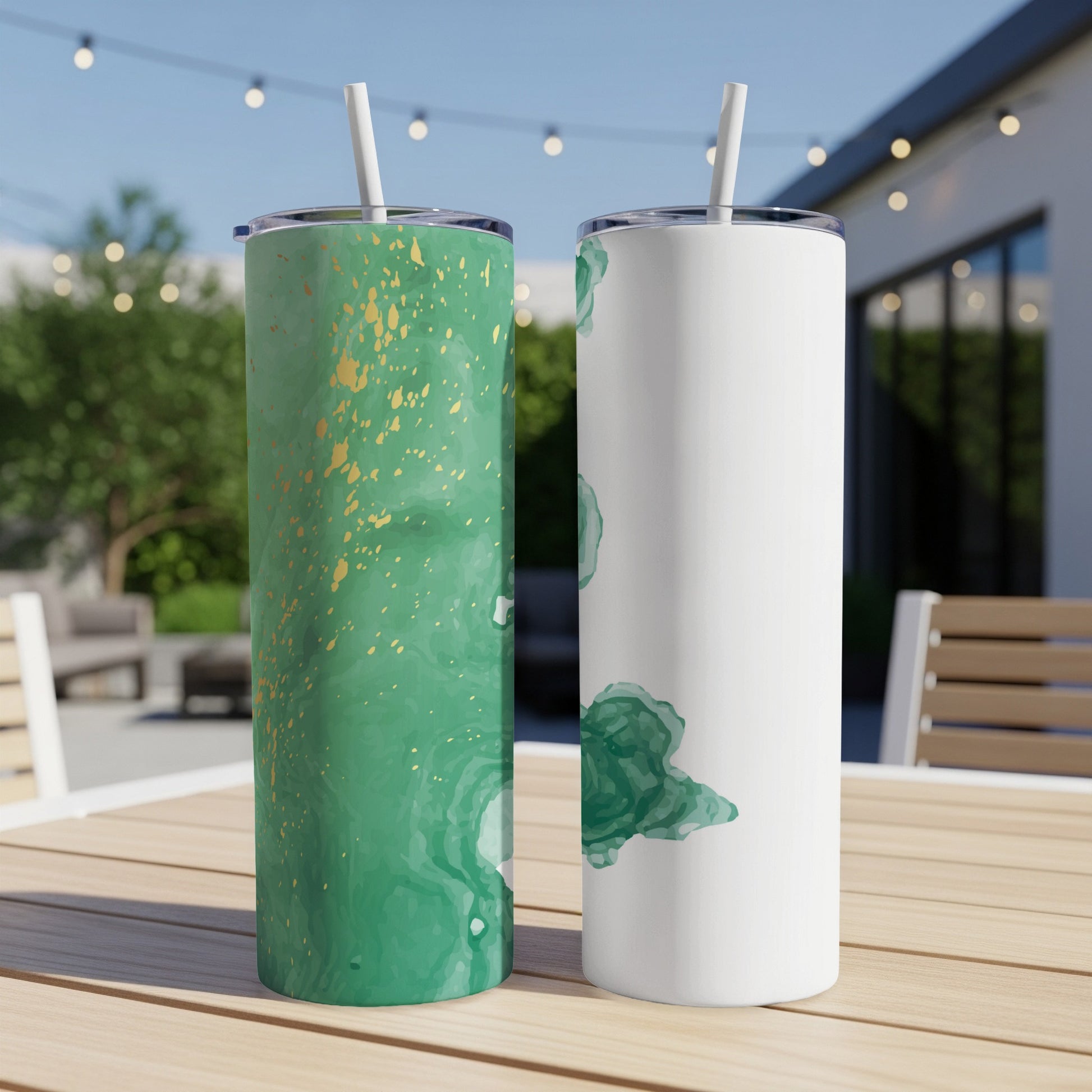 Two tumblers with green marble and gold splatter designs on a wooden table.