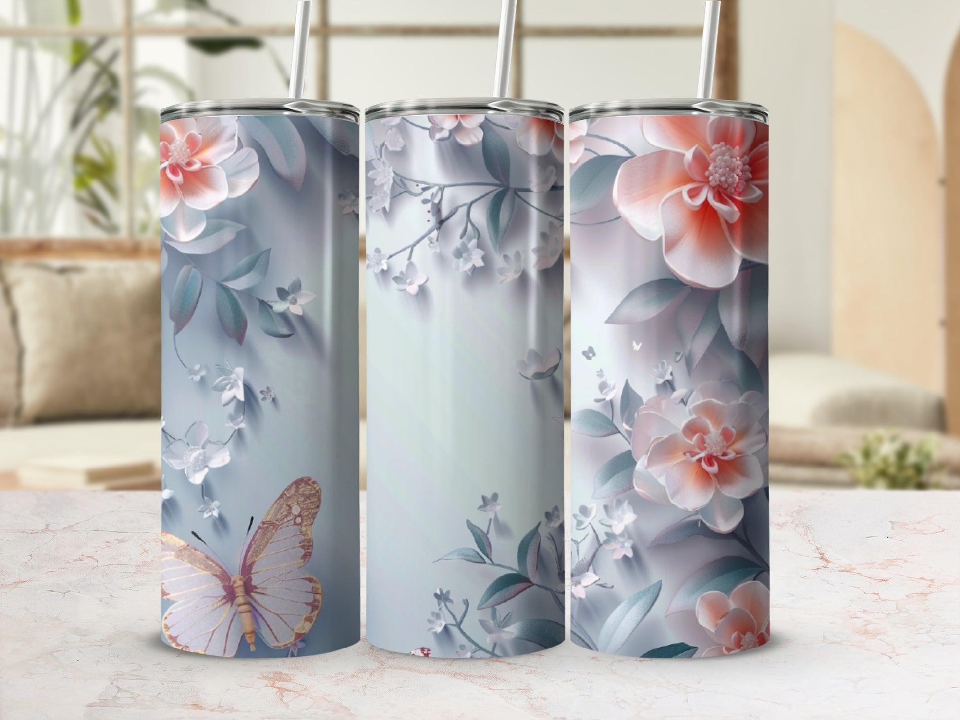 Three tumblers with floral and butterfly designs on a marble surface.