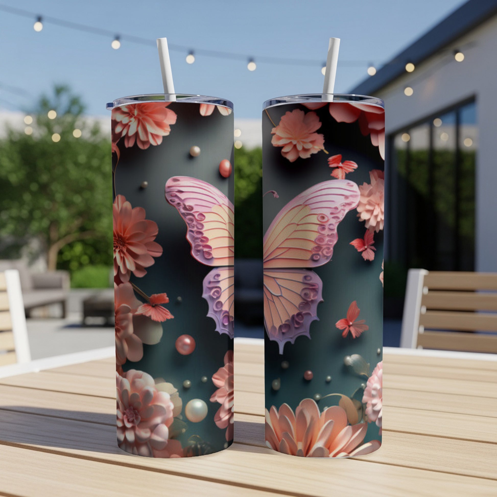 Two tumblers with a pink butterfly and floral design on an outdoor table.