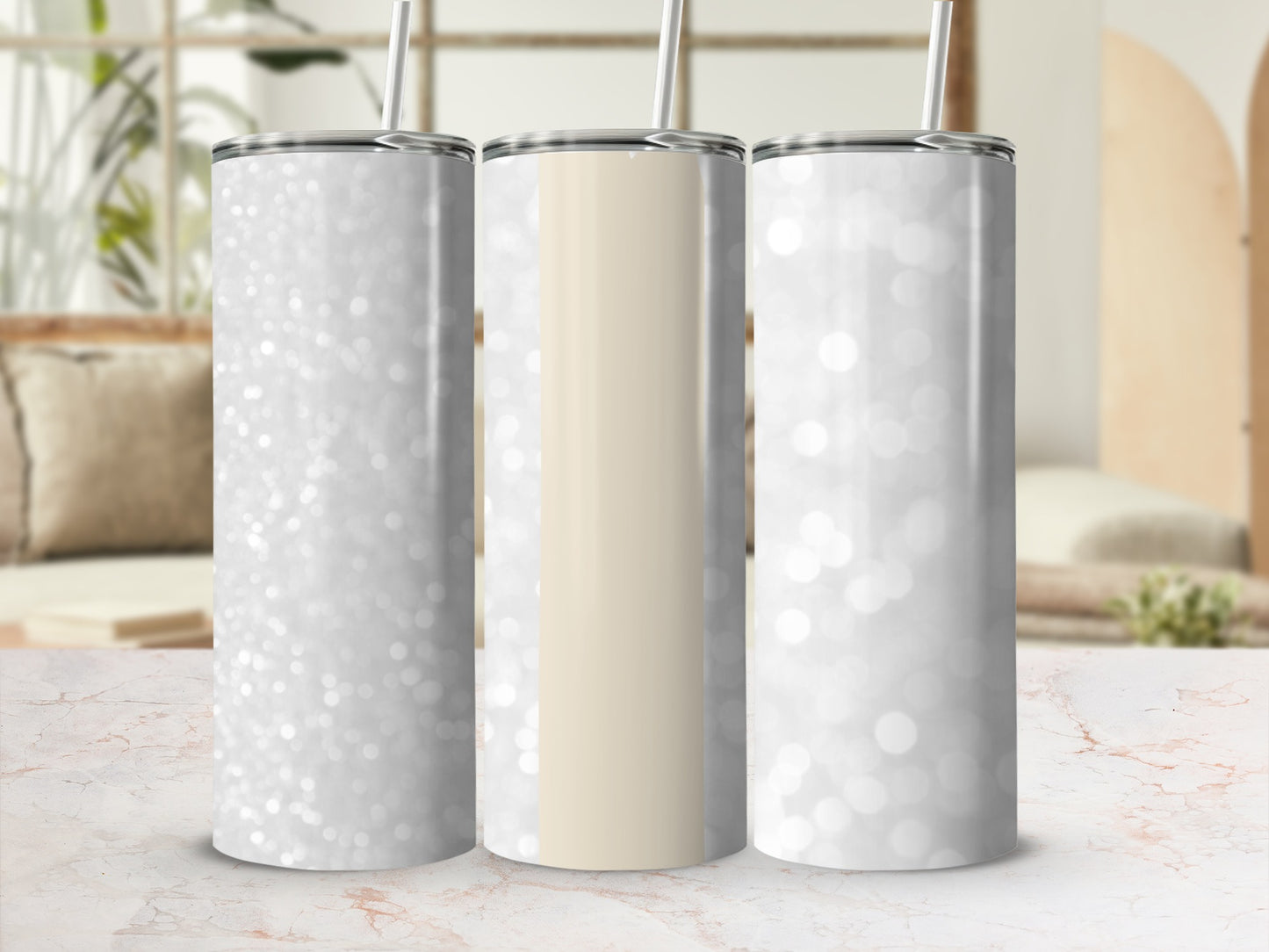 Three glitter tumblers with straw on marbled surface.
