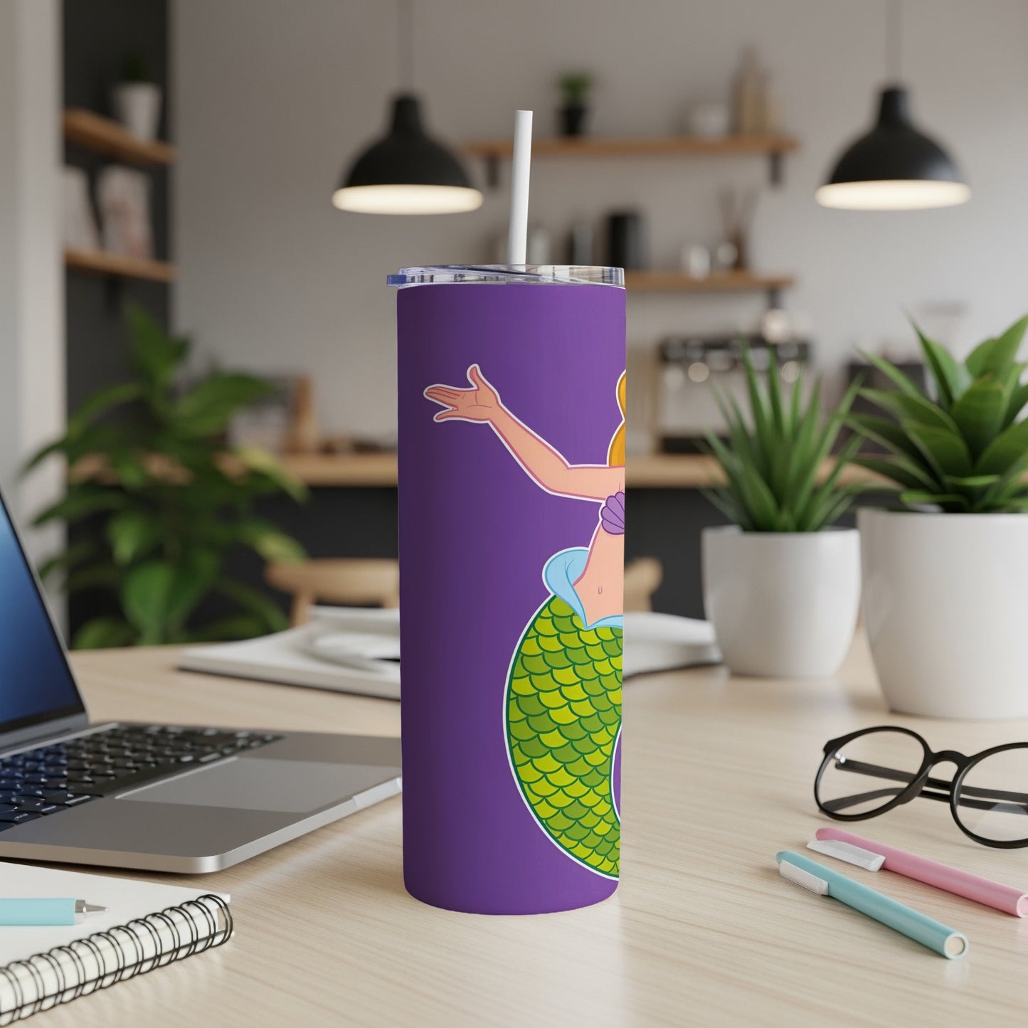 Purple tumbler with cartoon mermaid and straw on desk.