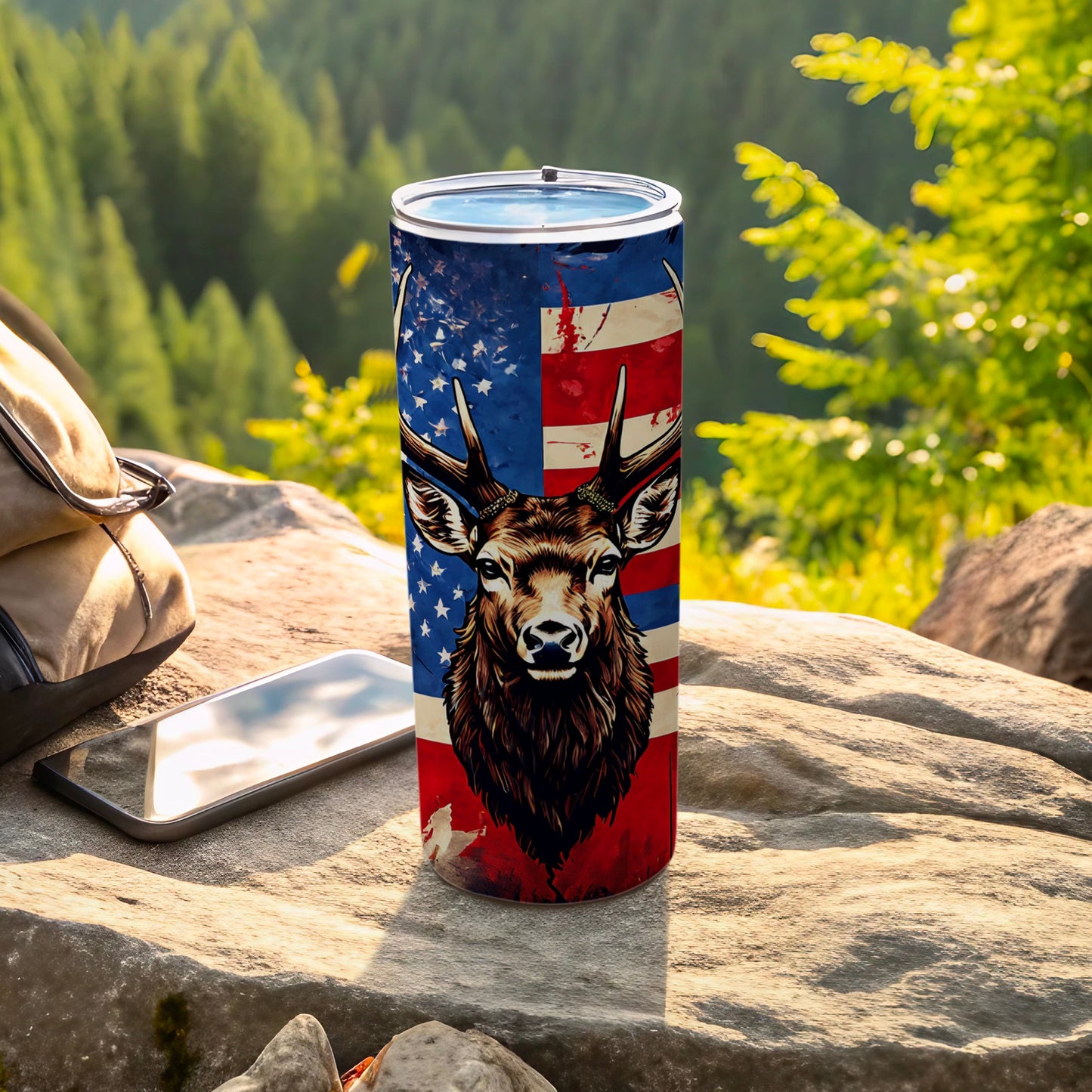 Tumbler with deer, American flag design, and backpack on rock.