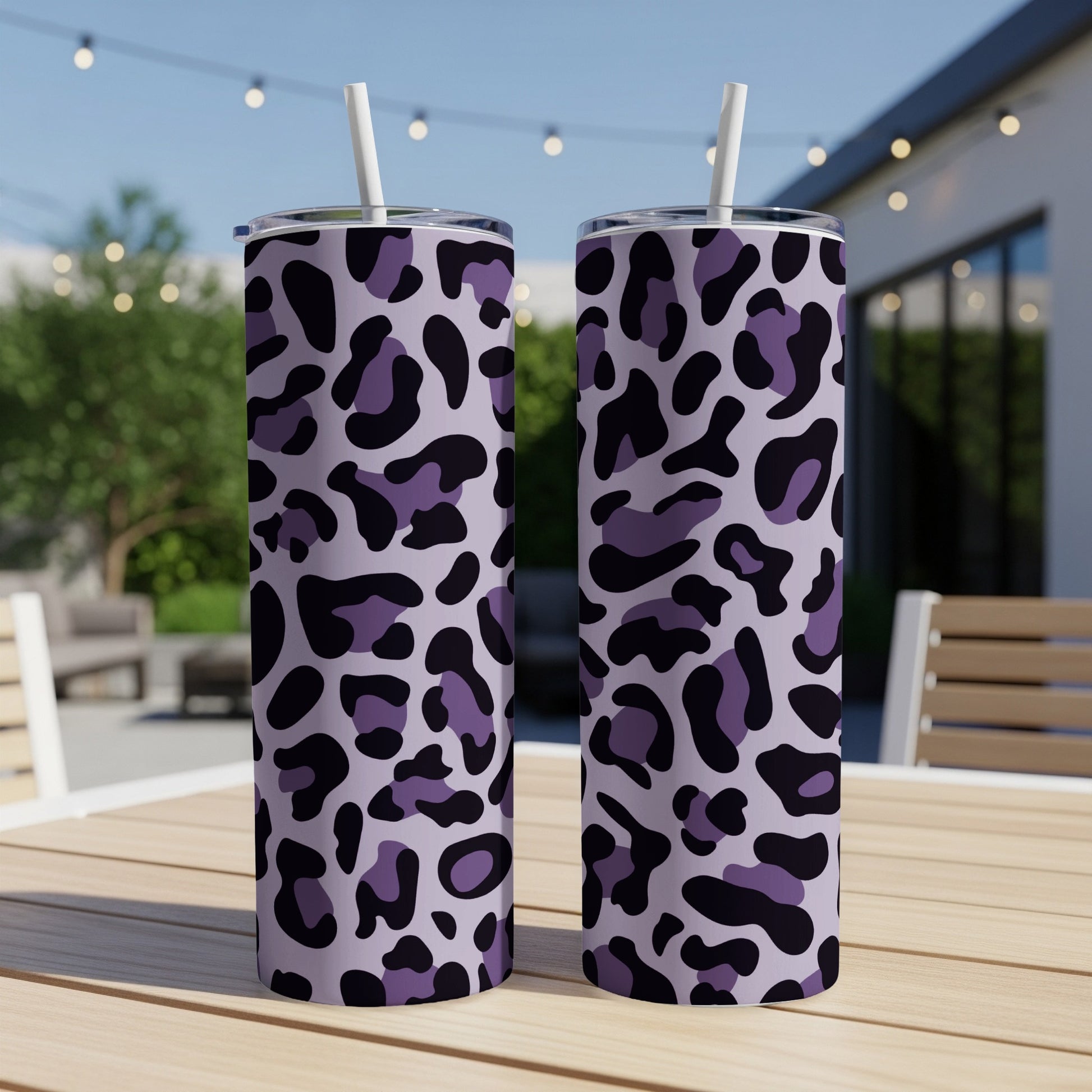 Two tall tumblers with a purple and black leopard print pattern sit on a table.