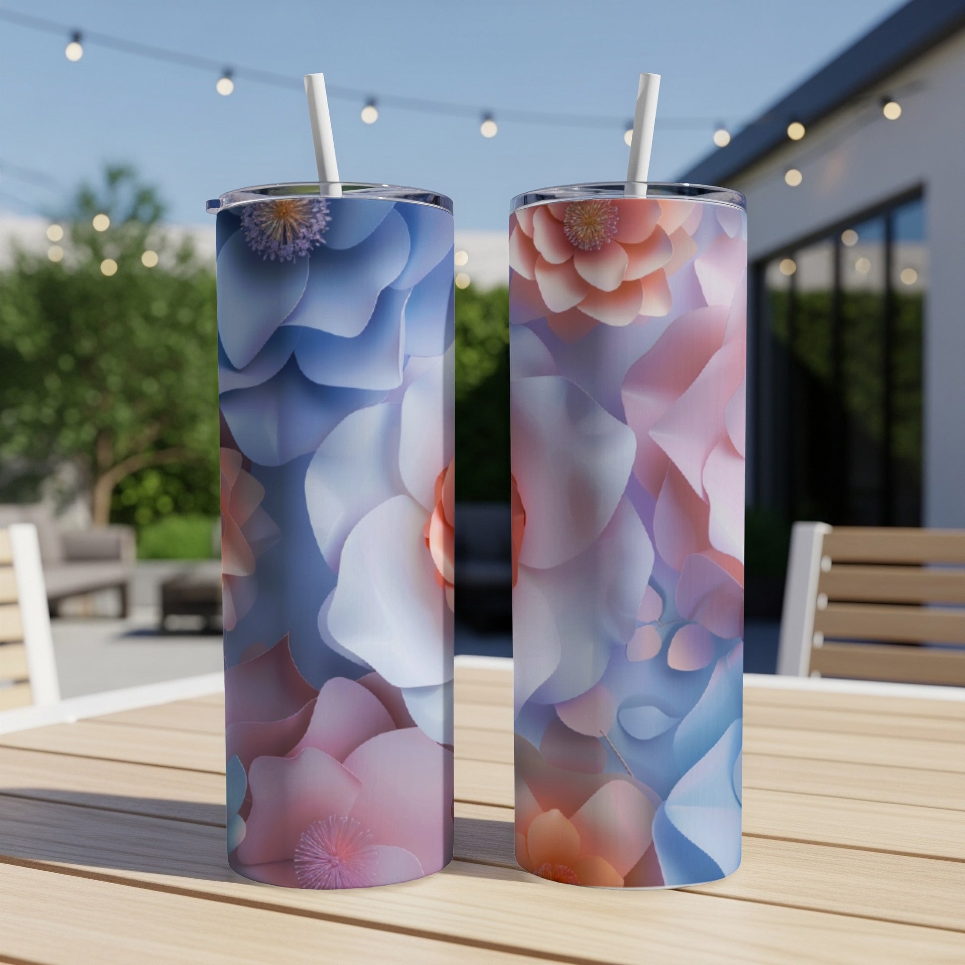 Two tall tumblers with pastel floral patterns and straws on a wooden table.