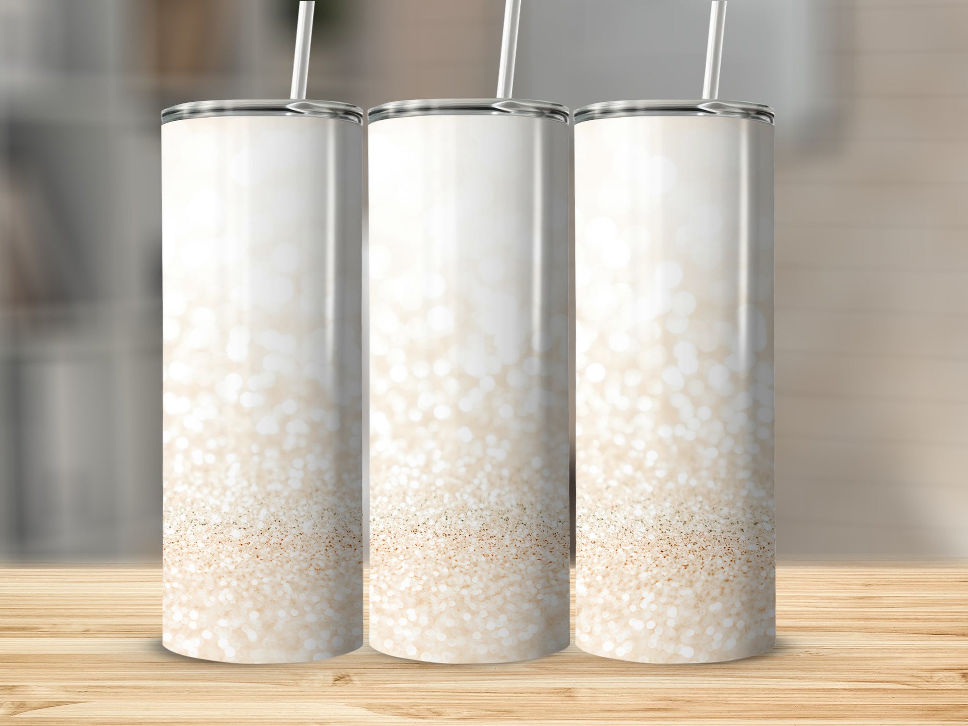 Three white tumblers with a champagne glitter gradient on a wooden surface.
