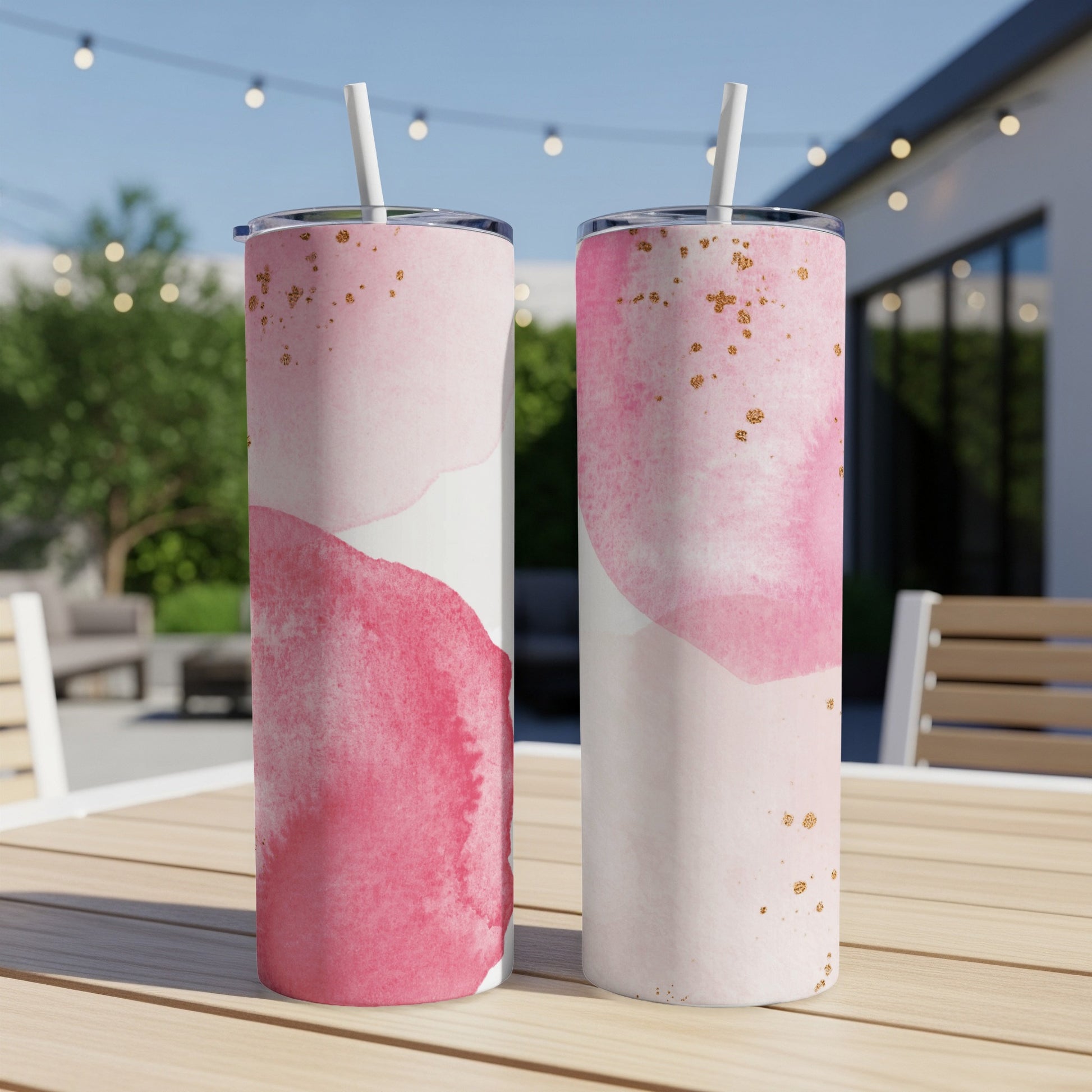 Two pink watercolor tumblers with gold flecks sit on a wooden table.