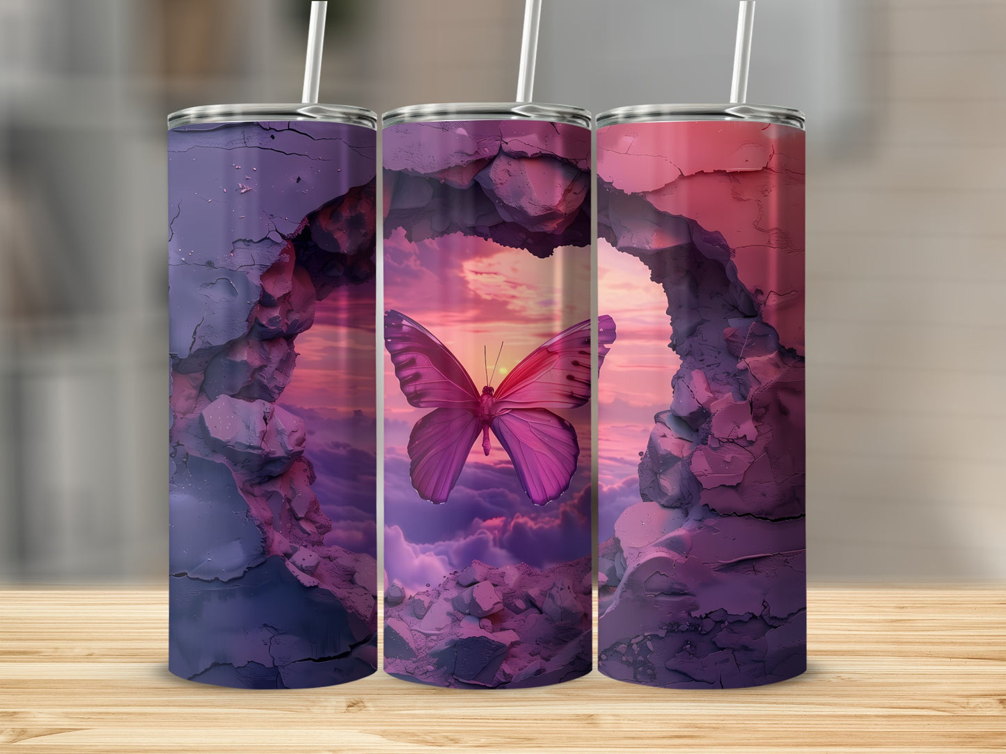 Three tumblers featuring a pink butterfly in a rocky archway at sunset.