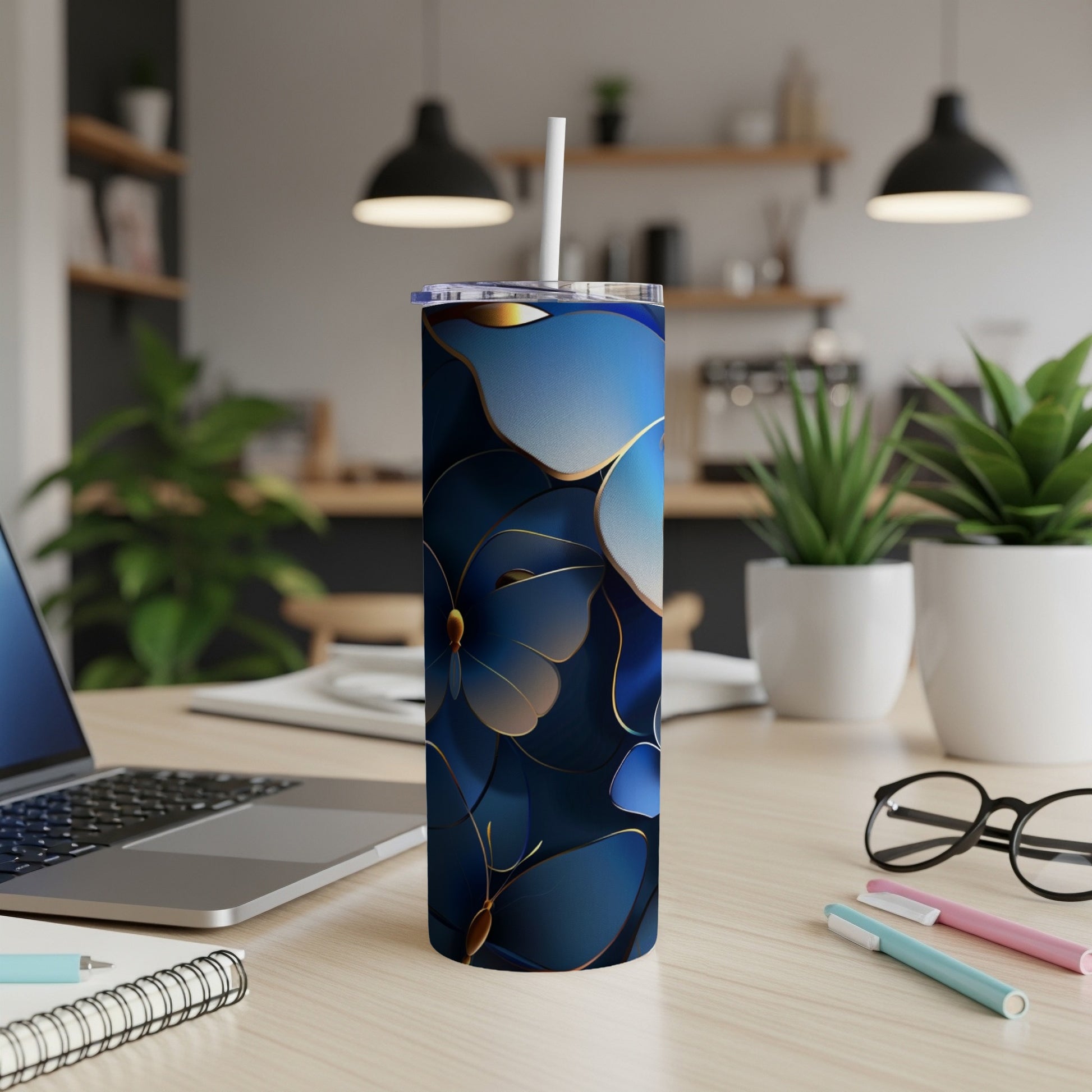 Blue and gold floral patterned tumbler with white straw on a desk.