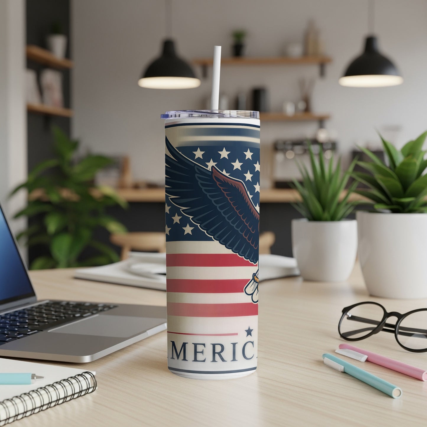 American flag tumbler with eagle, straw, laptop, and pens.