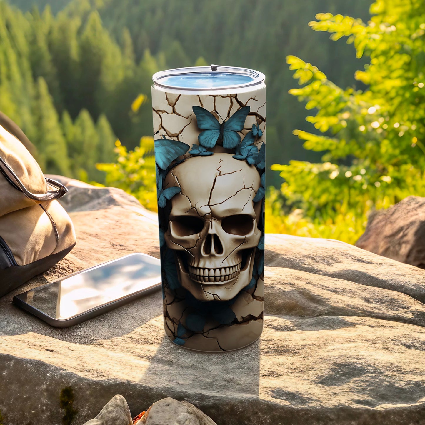 Cracked skull tumbler with blue butterflies, displayed outdoors.