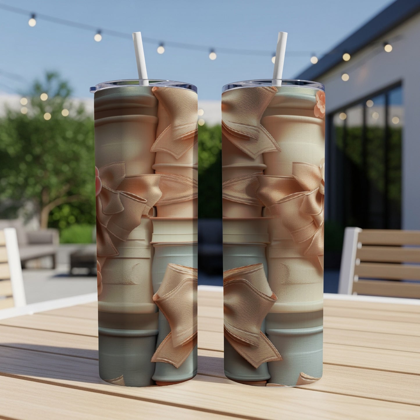 Two tumblers with a light pink ribbon and bow pattern sit on a patio table.