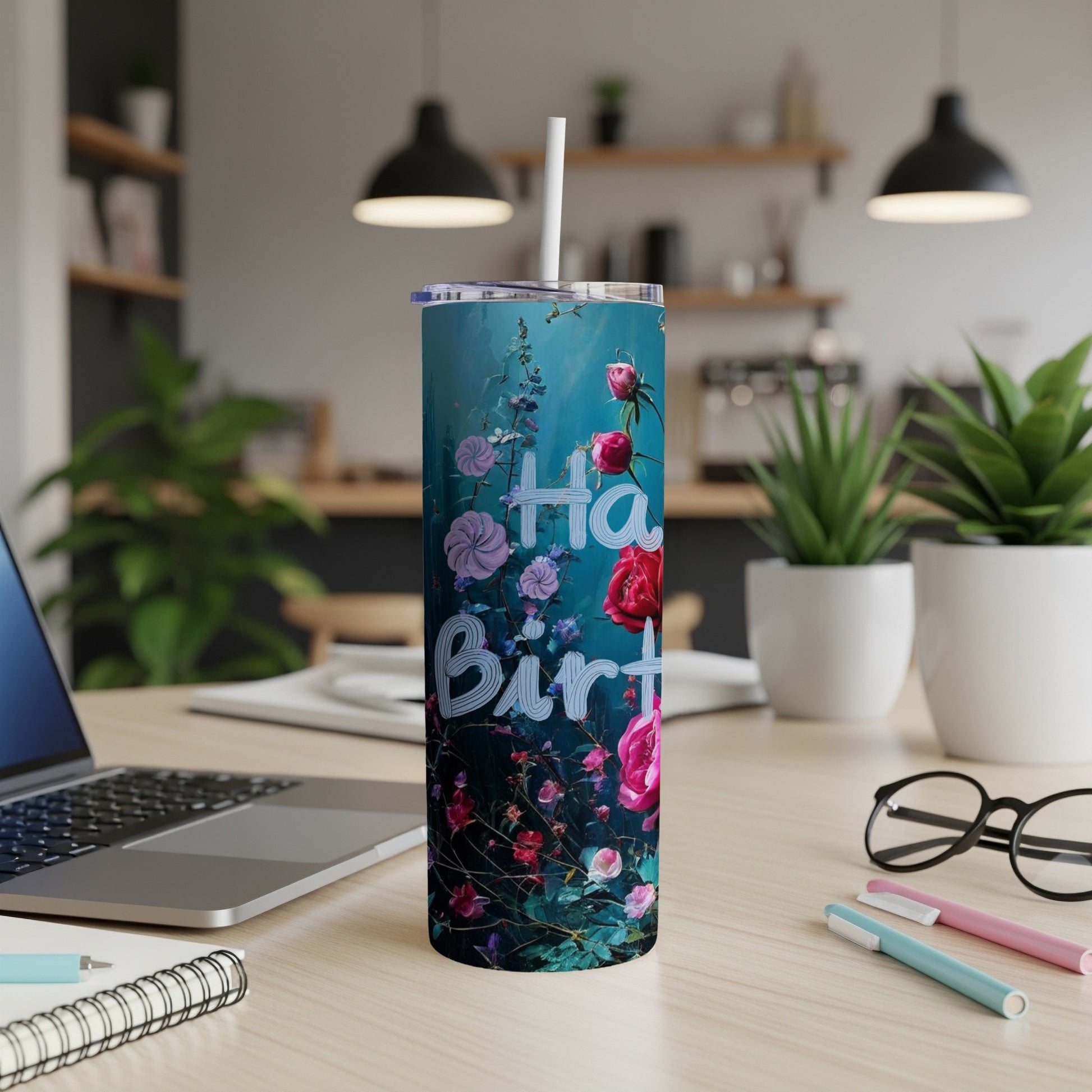 Floral design tumbler with "Happy Birthday" text on a desk.