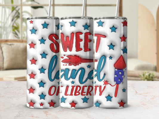 Tumbler with "Sweet Land of Liberty" and fireworks, set against a blurred background.