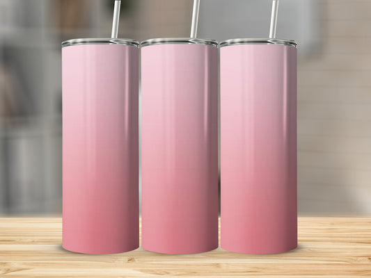 Three pink gradient tumblers with straws on a wooden surface.