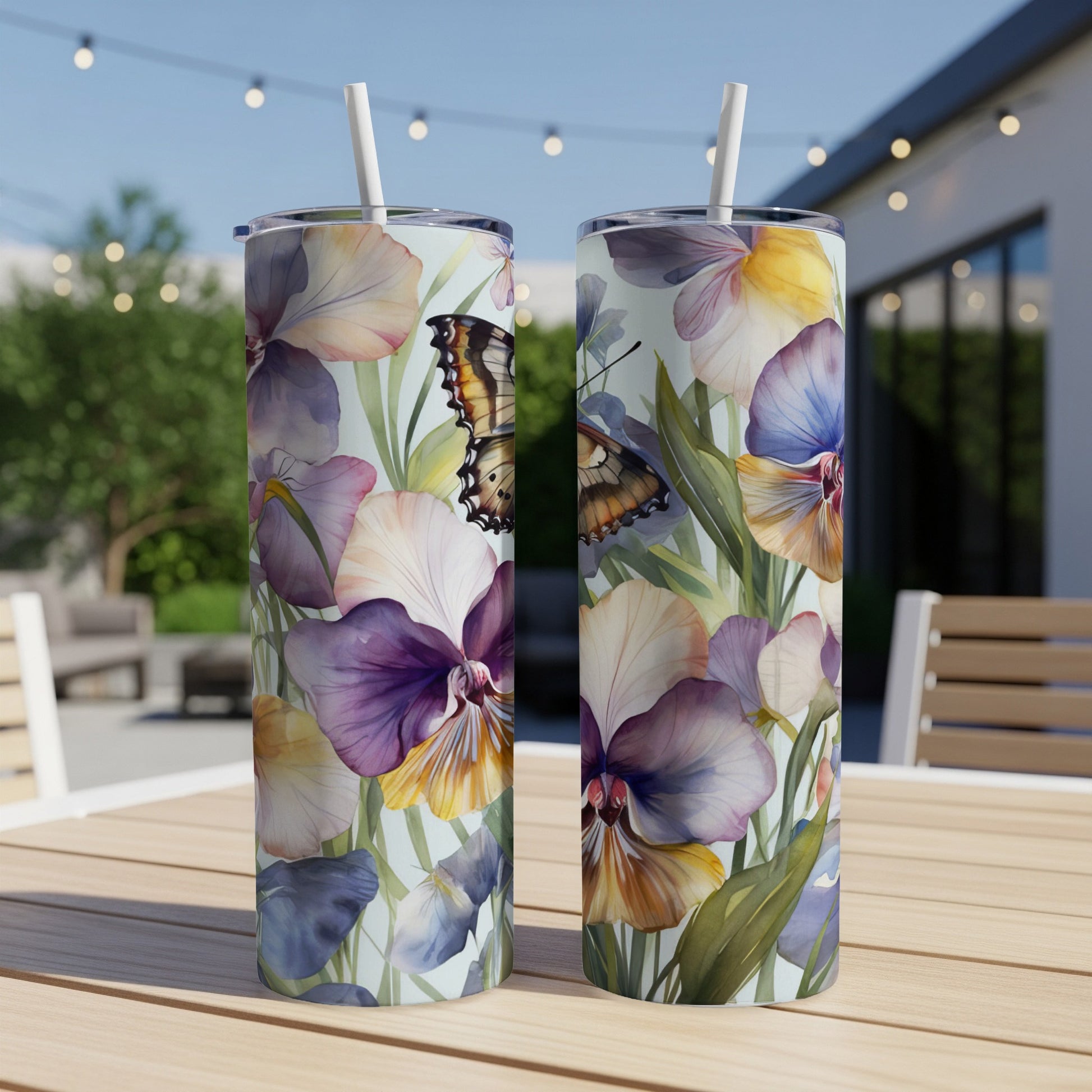 Two tall tumblers with colorful pansies and butterfly design on a table.