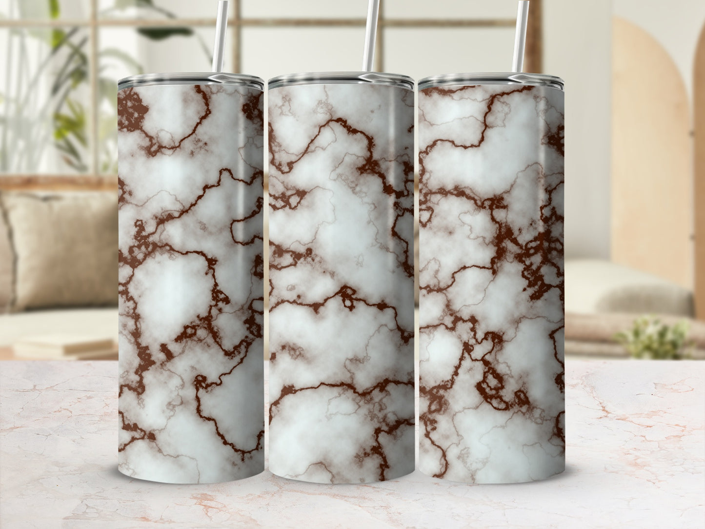 Three marble print tumblers with brown veins and straws, displayed on a counter.