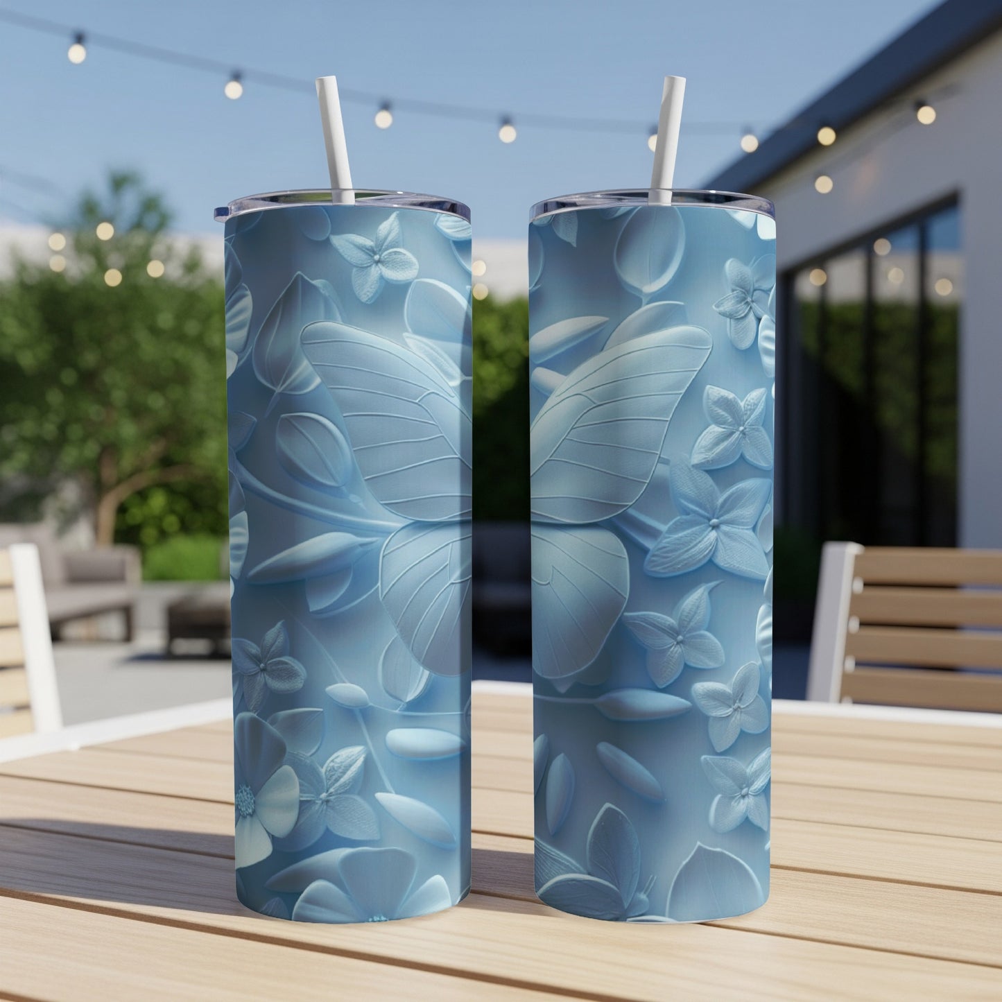 Two light blue tumblers with embossed butterfly and floral designs sit on a table.