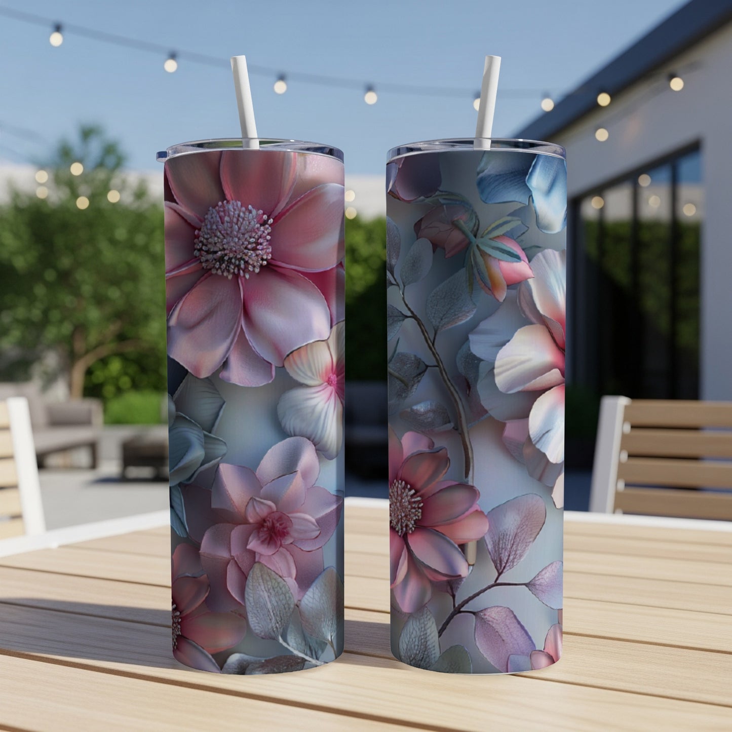 Two pink and blue floral patterned tumblers with straws sit on a wooden table.