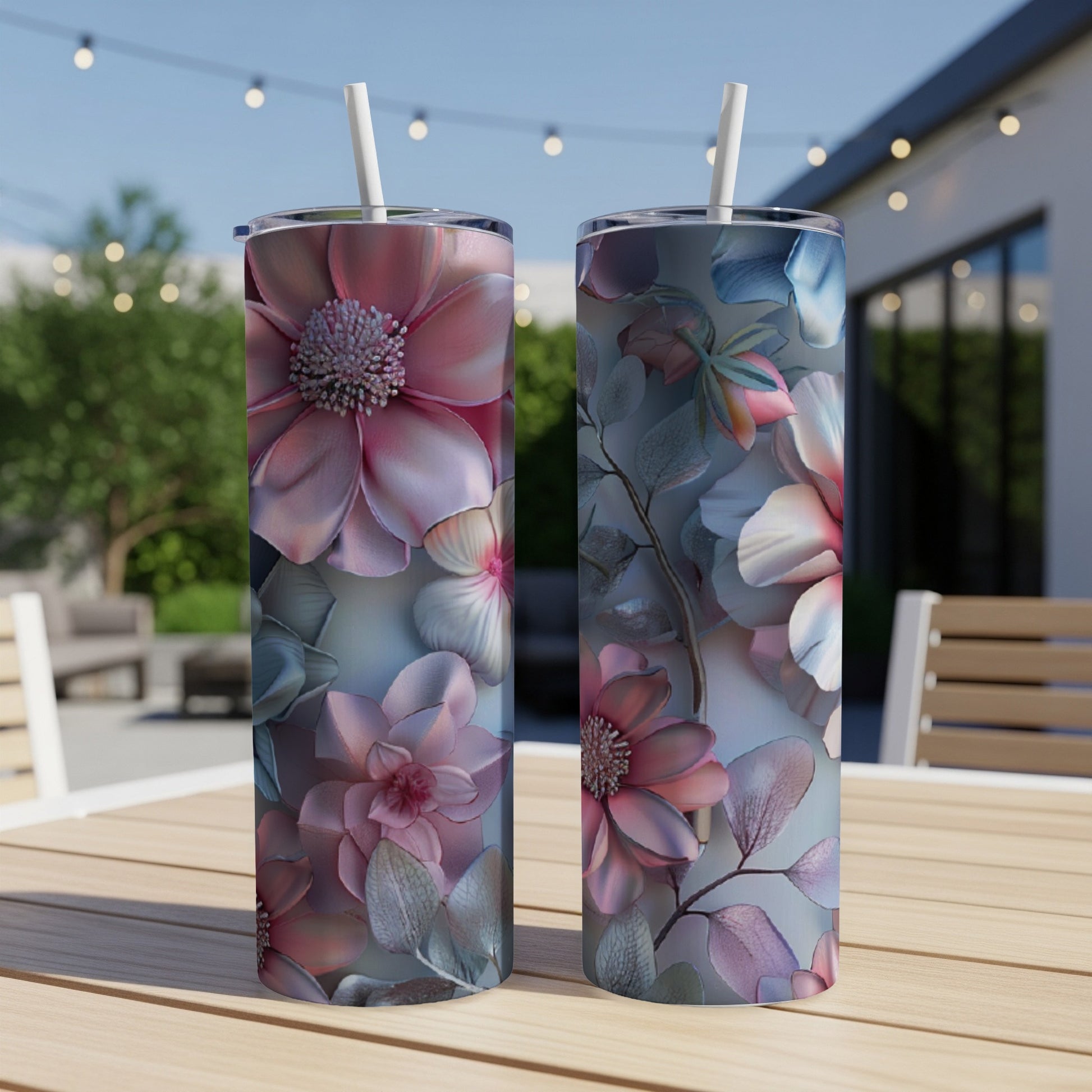 Two pink and blue floral patterned tumblers with straws sit on a wooden table.