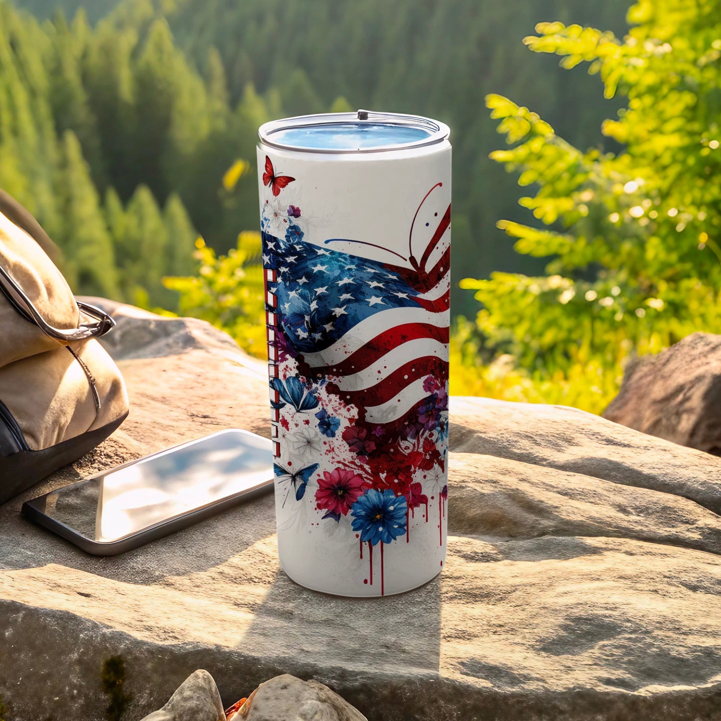 White tumbler with American flag and butterfly design, outdoors.