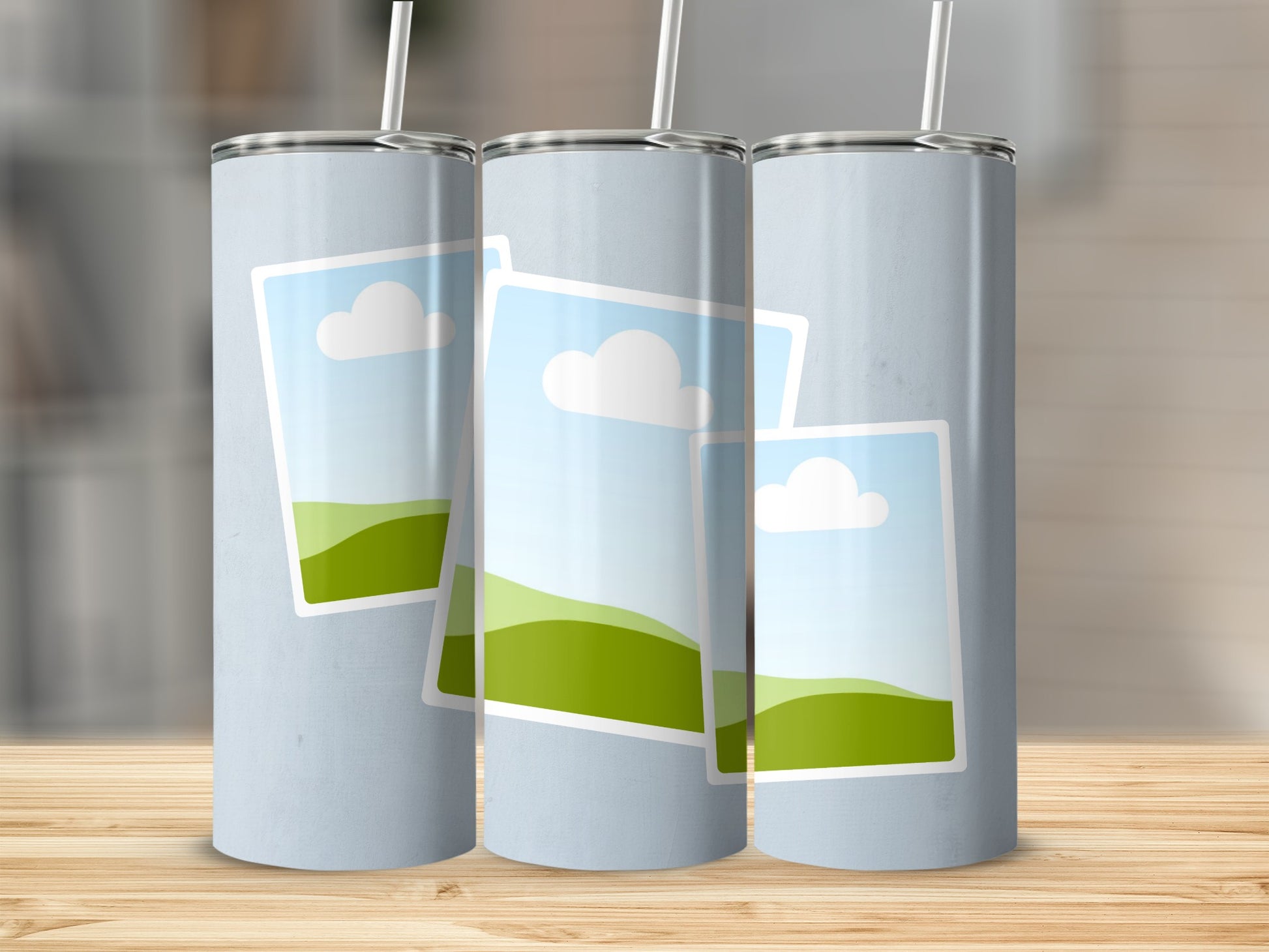 Three light blue tumblers with straw feature layered landscape images.