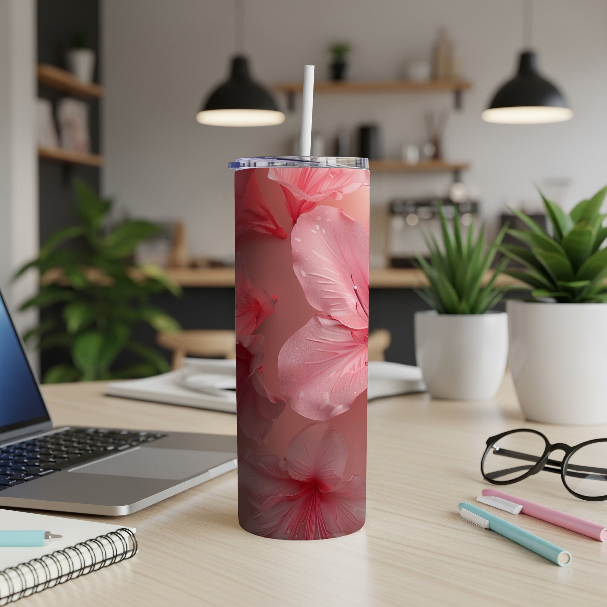 Pink hibiscus flowers on a skinny tumbler with a straw.
