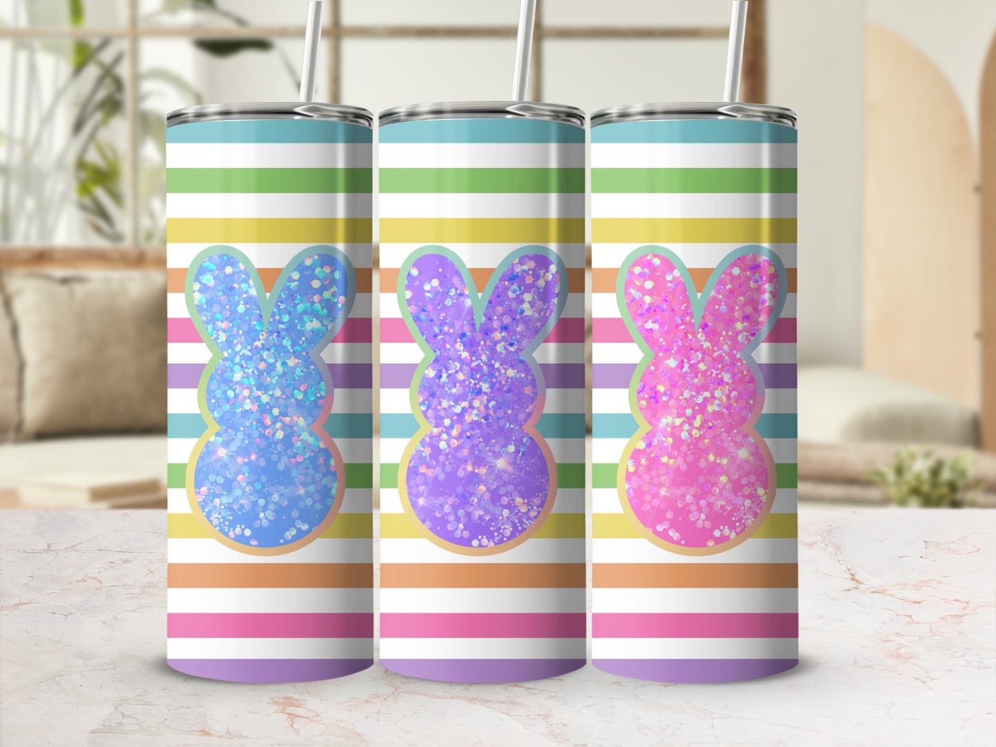 Three glitter bunny tumblers with colorful stripes, on a marbled surface.