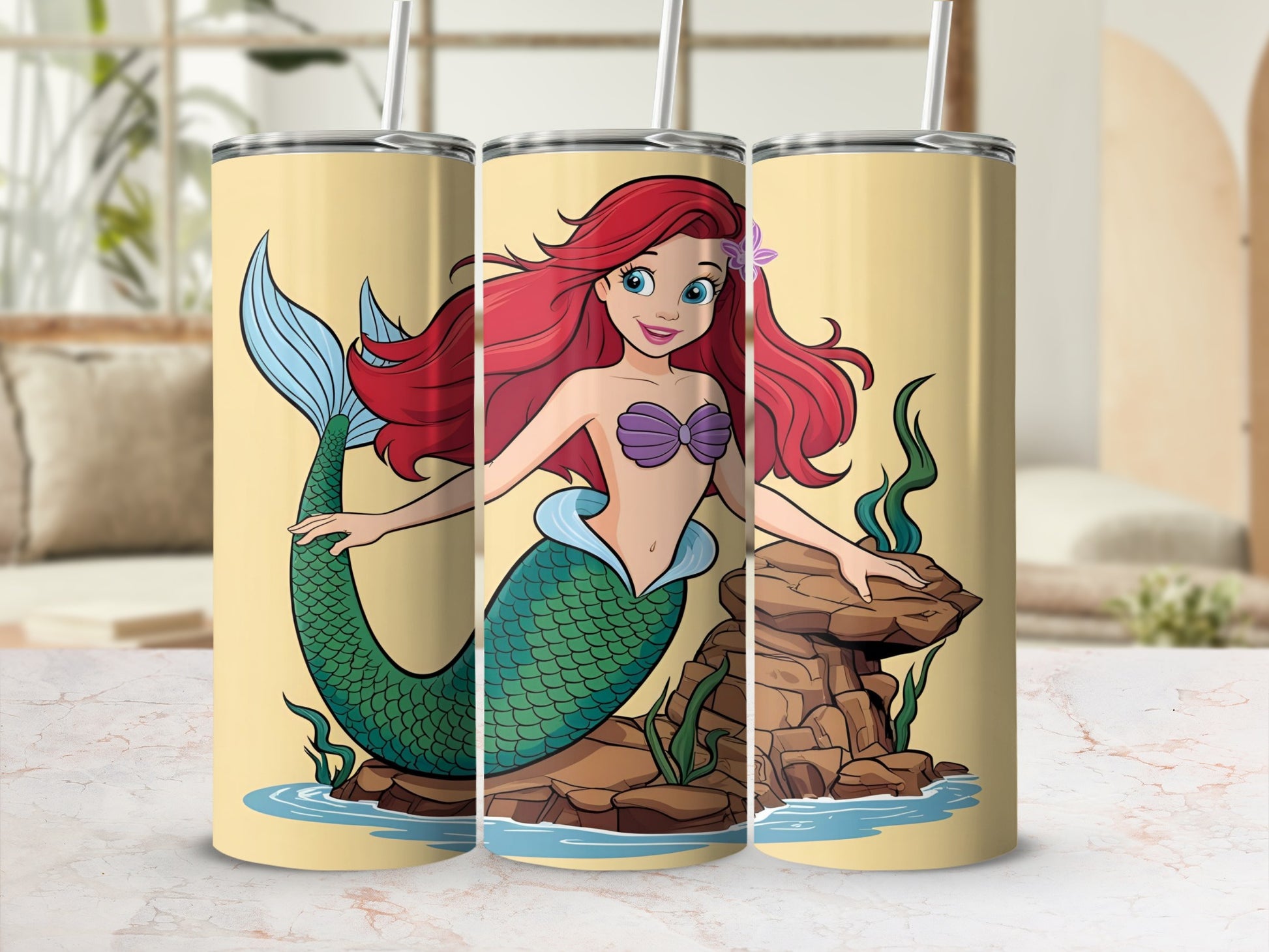 Ariel the mermaid on a tumbler with rocks and water.