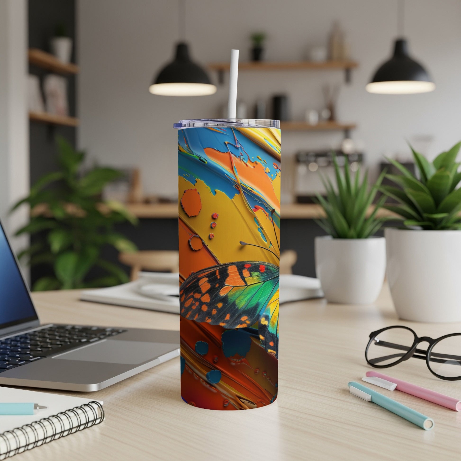 Colorful butterfly tumbler with straw on a desk, close-up view.