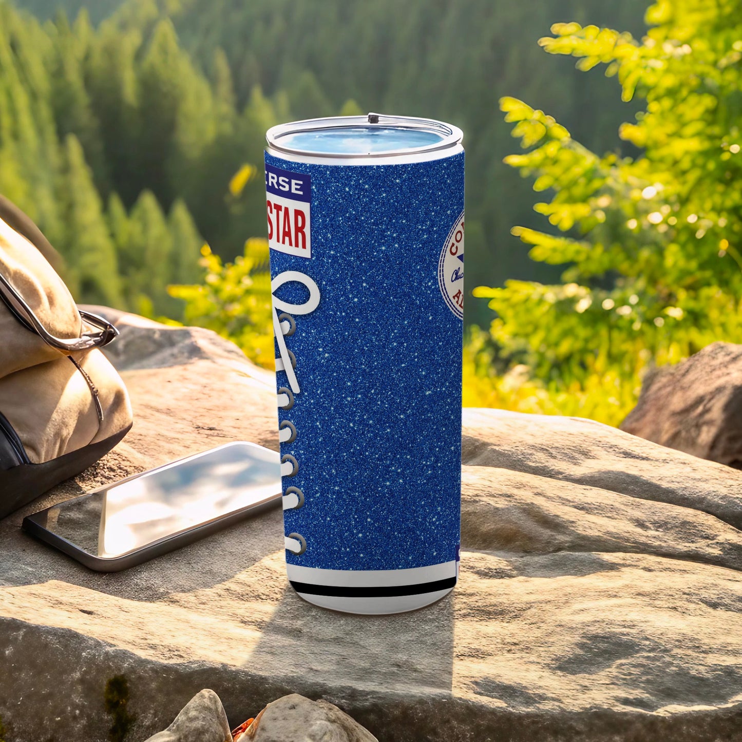 Blue glitter Converse tumbler with white laces, next to a phone and backpack.