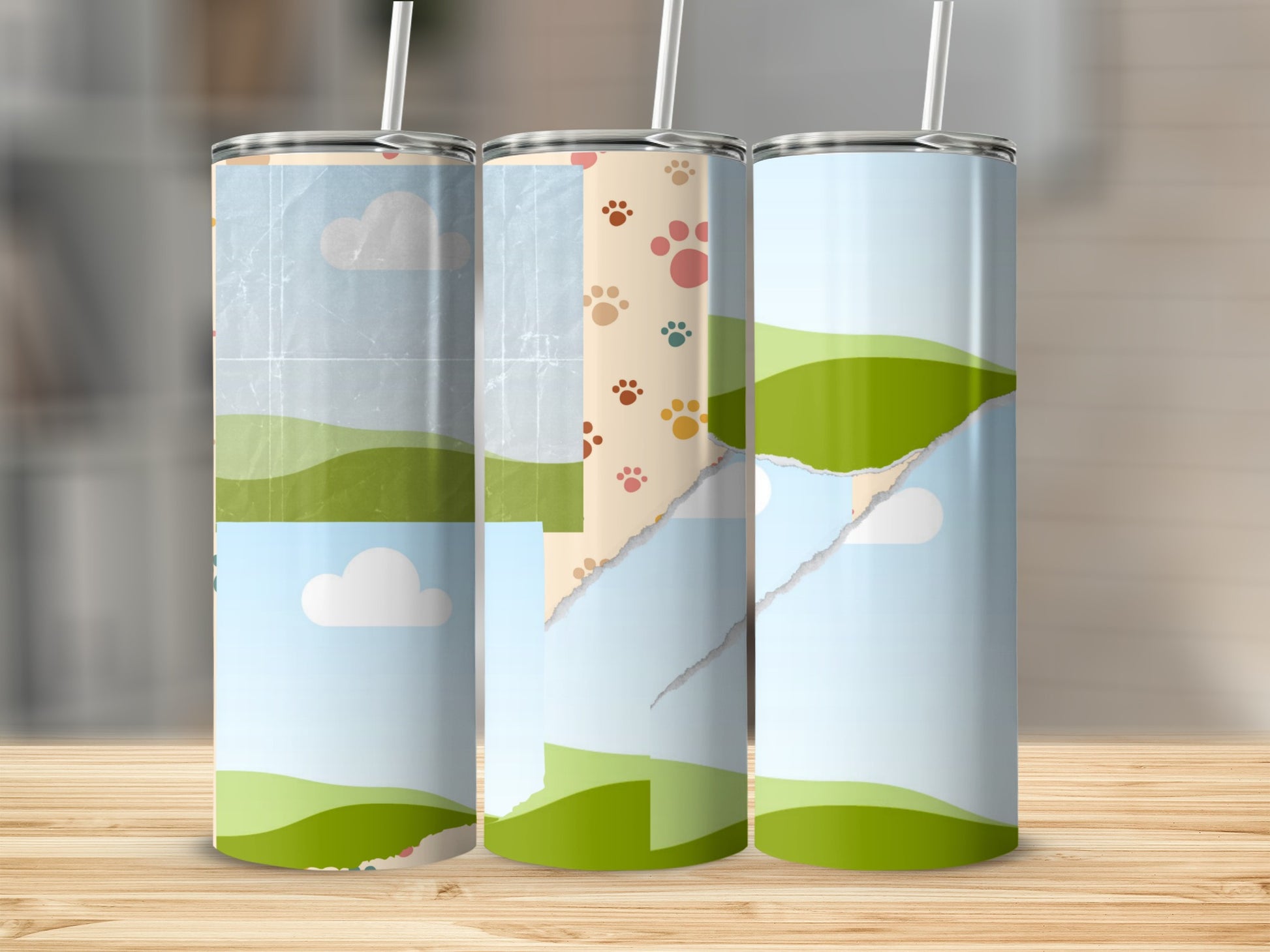 Three tumblers with a torn paper collage design featuring clouds, hills, and paw prints.