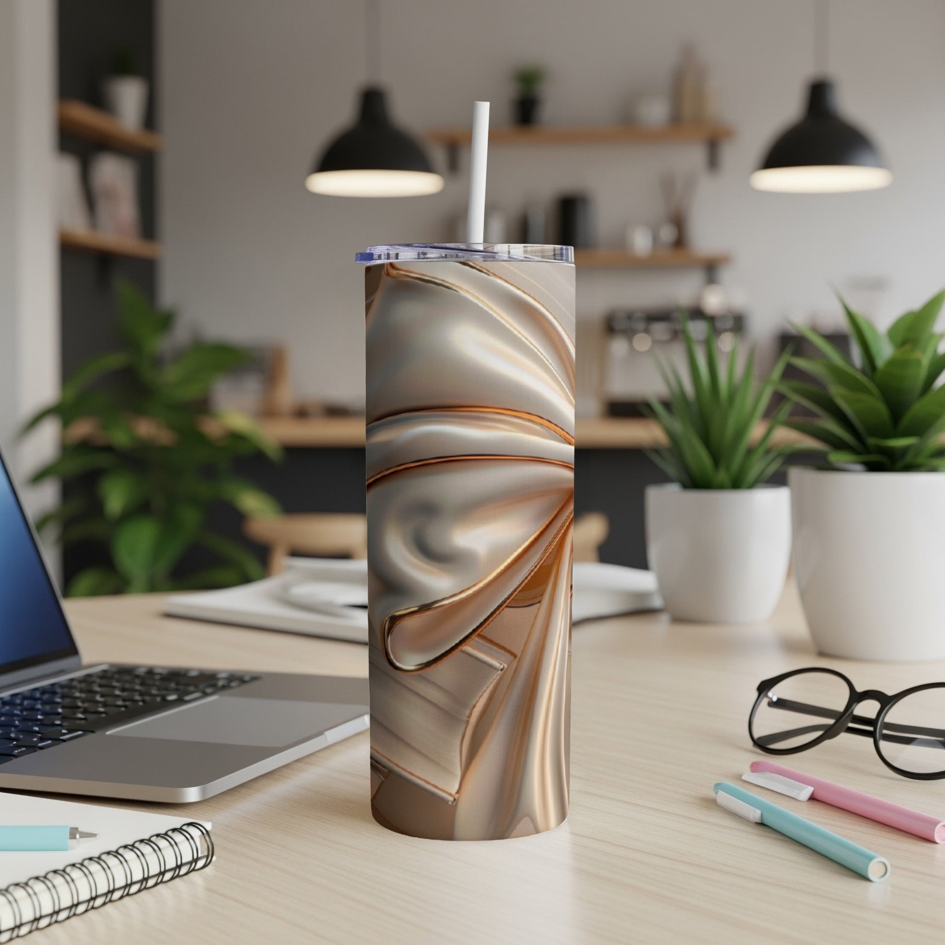 Metallic floral pattern tumbler with straw on a desk.