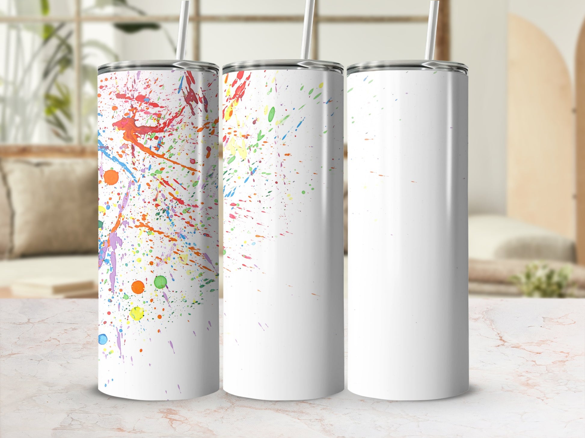 Three white tumblers with colorful paint splatter designs.