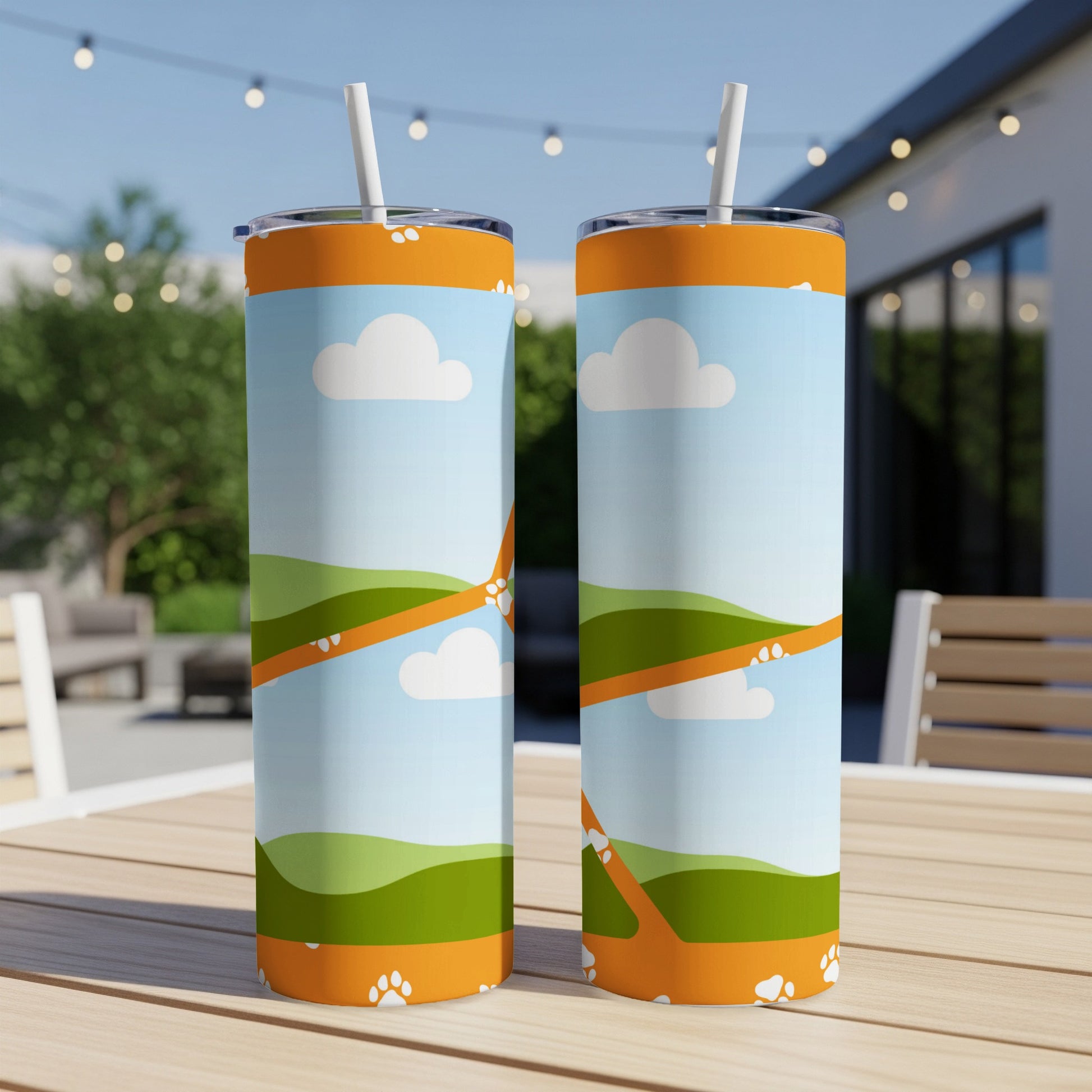 Two tumblers with a cartoon landscape, clouds, and paw prints.