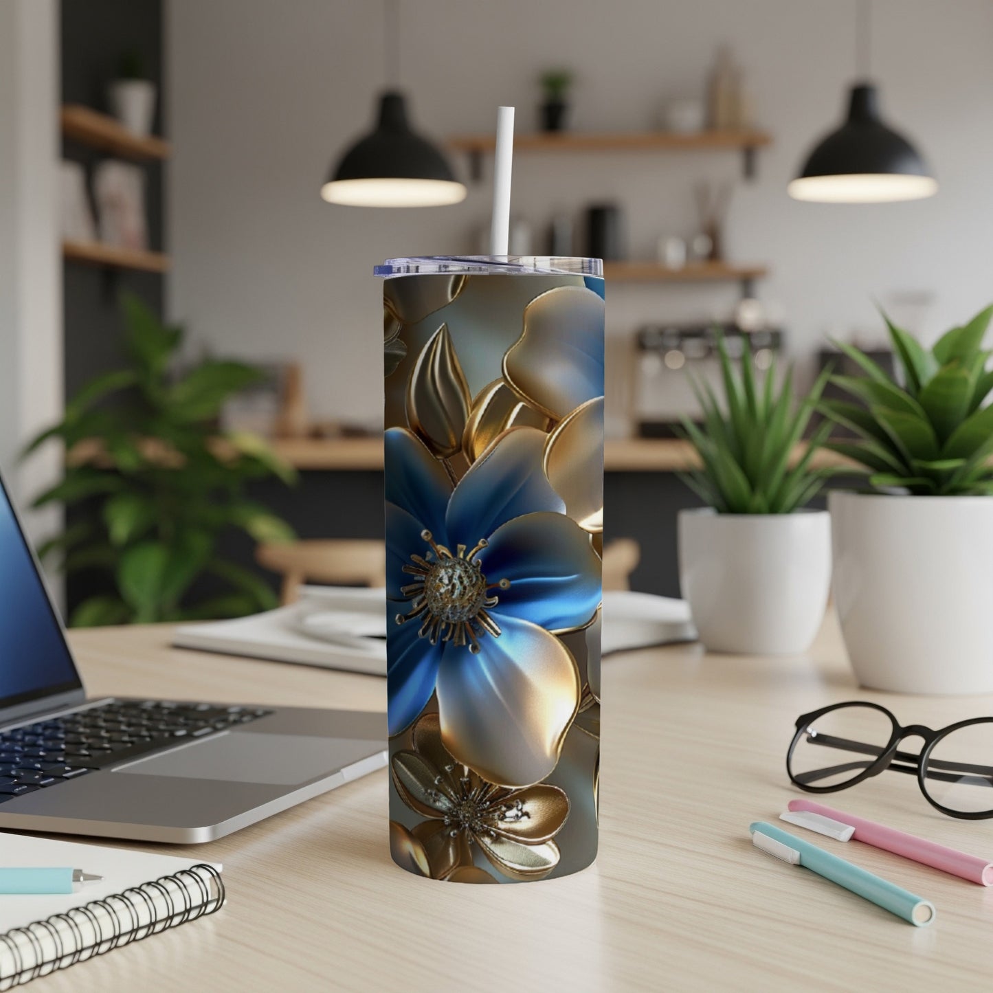 Blue and gold floral patterned tumbler on a desk with laptop and pens.