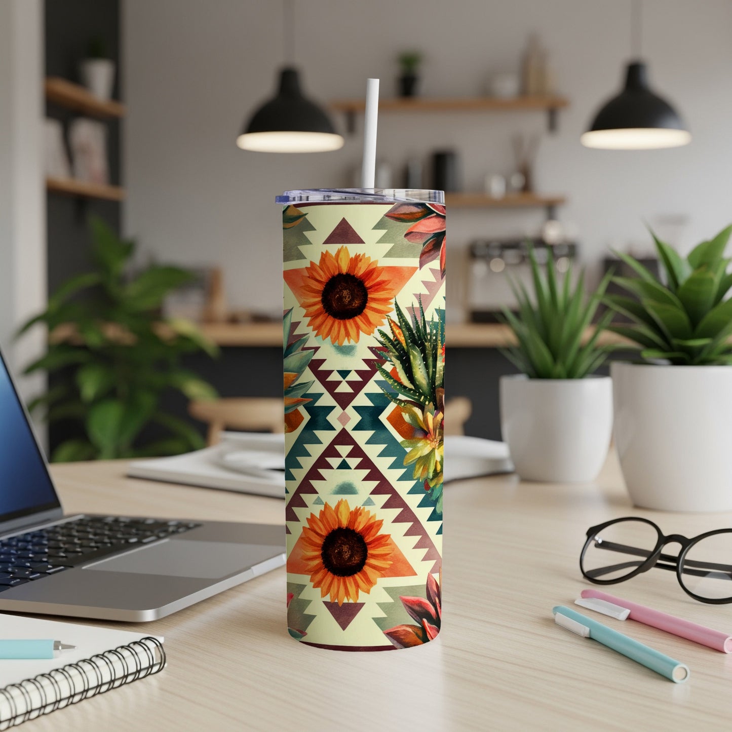 Floral and geometric patterned tumbler with straw, on a desk.
