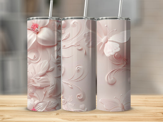 Pink floral and butterfly tumbler with straw on a wooden surface.