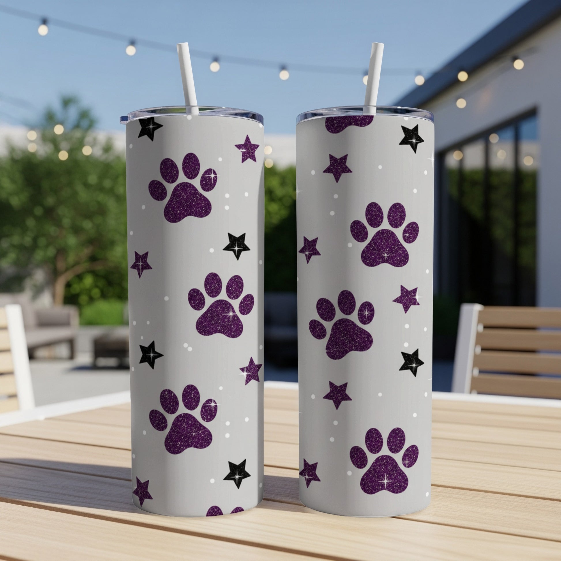 Two gray tumblers with purple glitter paw prints and white stars.