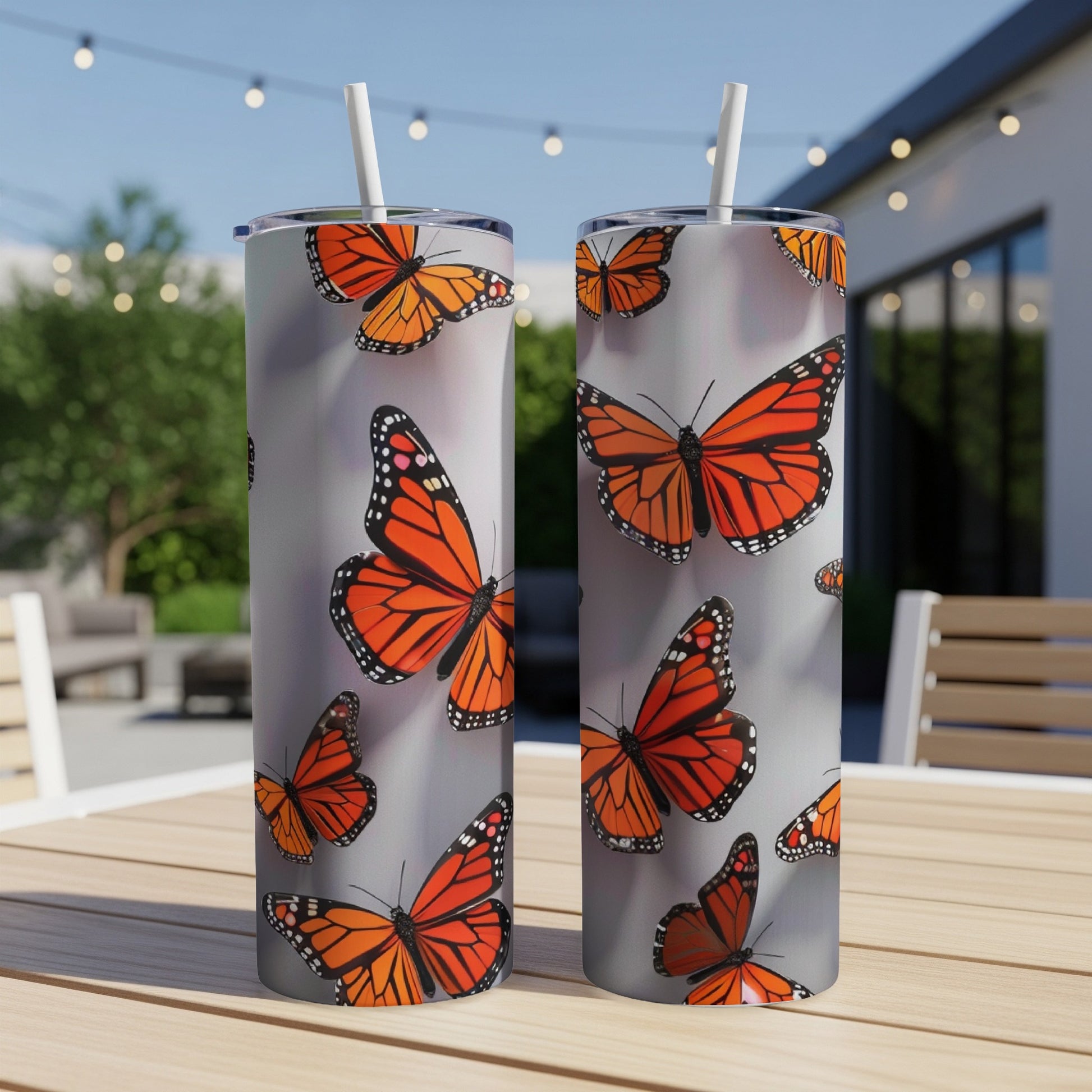 Two tall tumblers with orange monarch butterflies on a gray background.