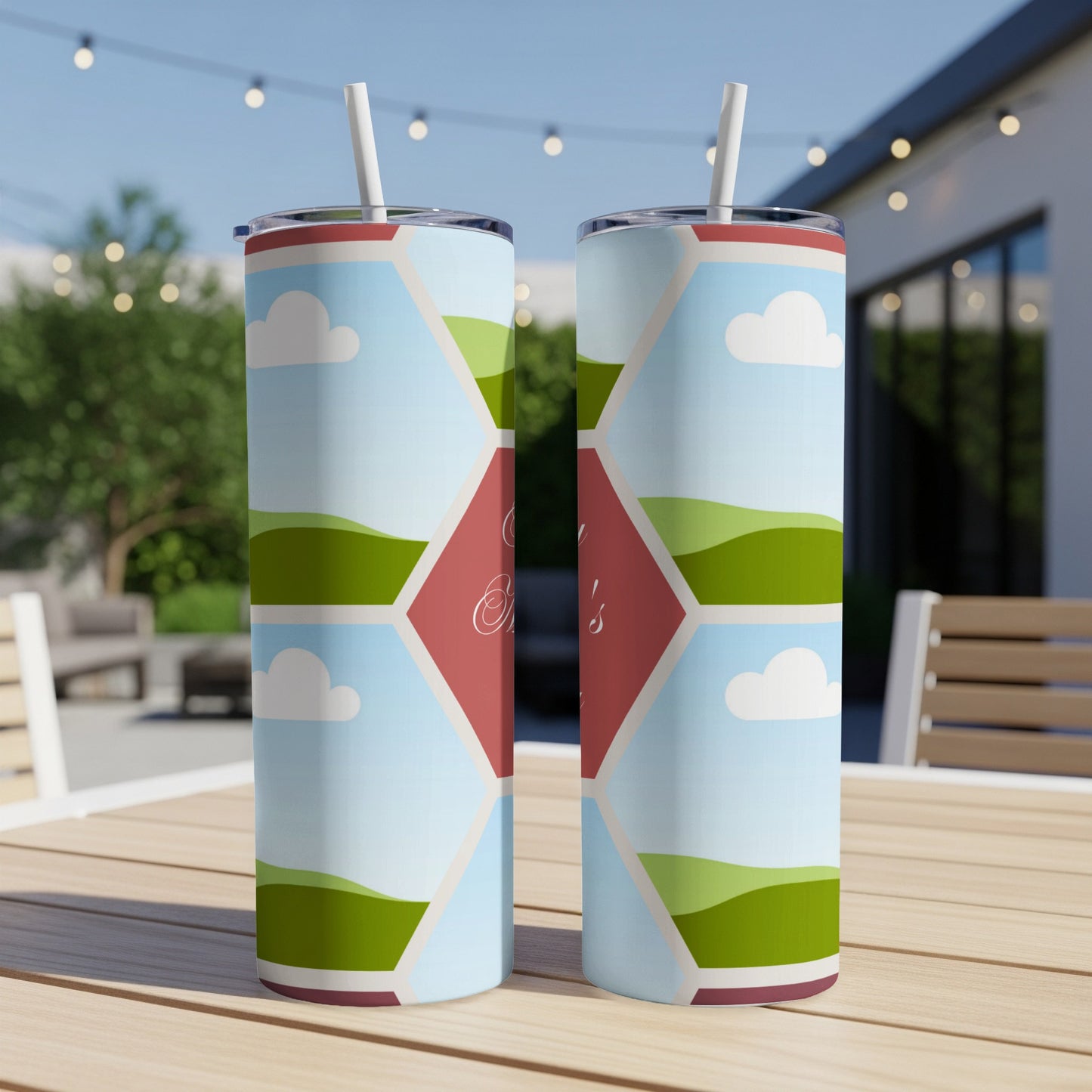Two tall tumblers with a landscape pattern and personalized text on a table.