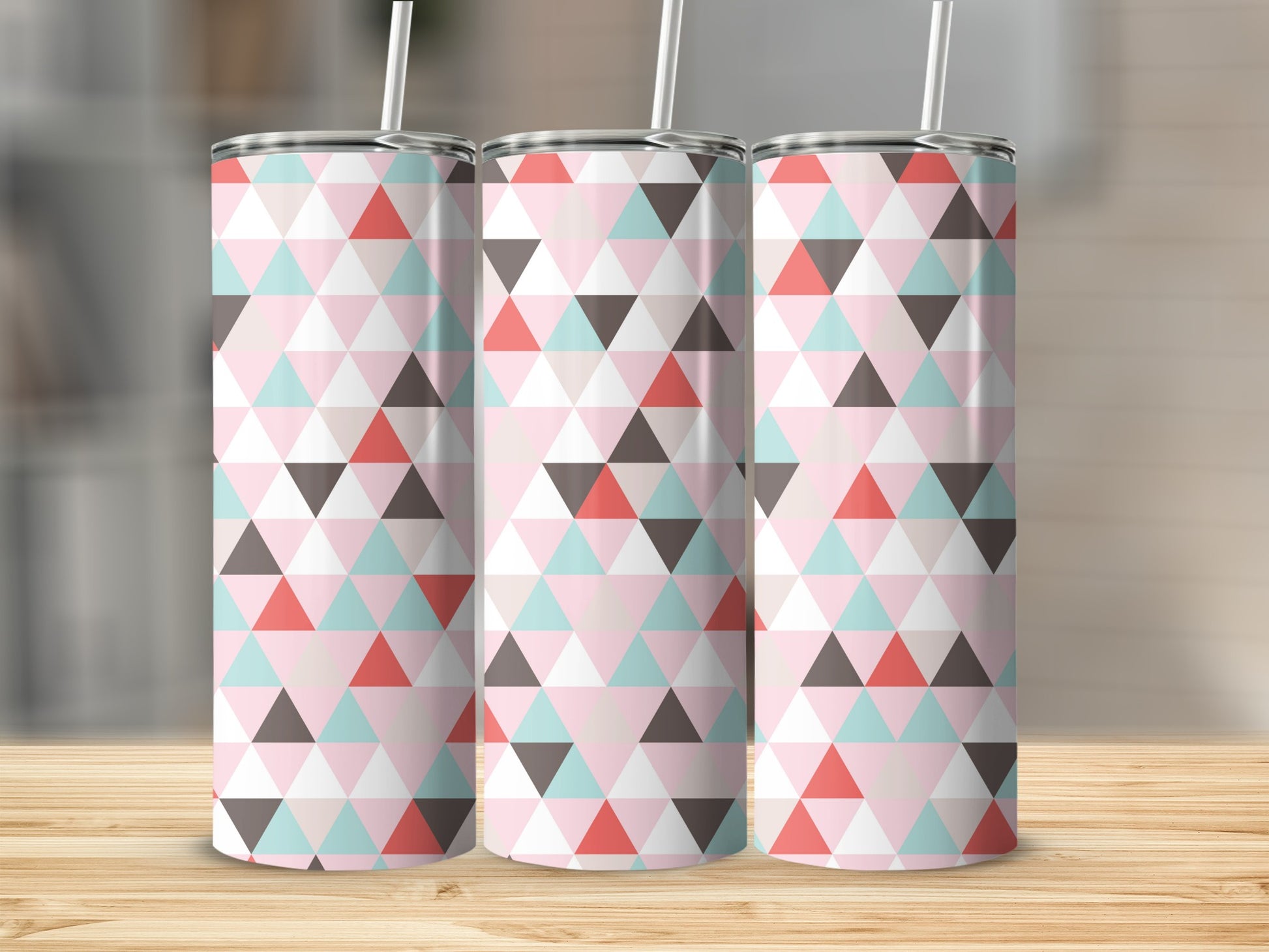 Three skinny tumblers with a geometric triangle pattern in pink, coral, teal, and taupe.
