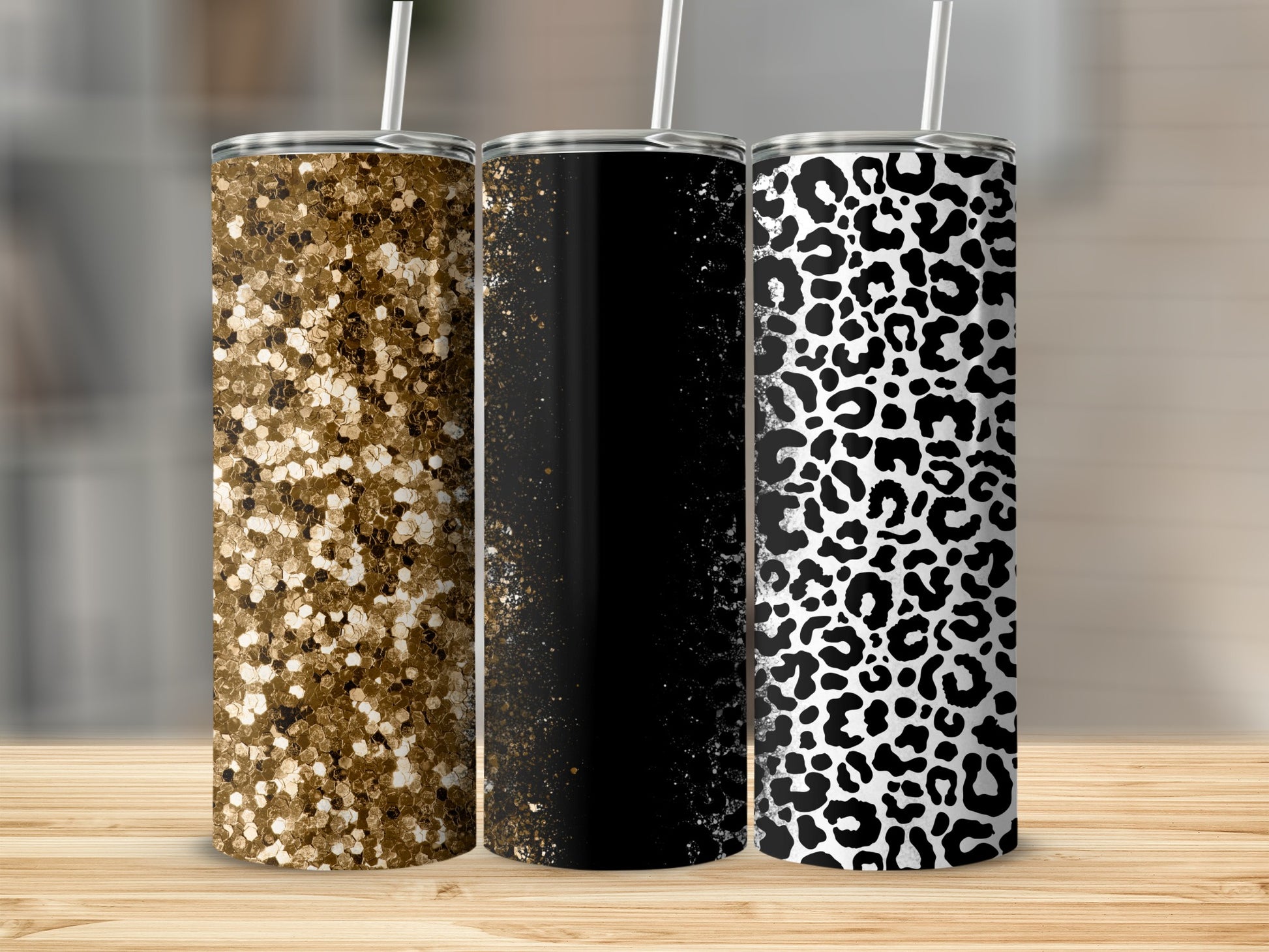 Three glitter, paint splatter, and leopard print tumblers with straws.