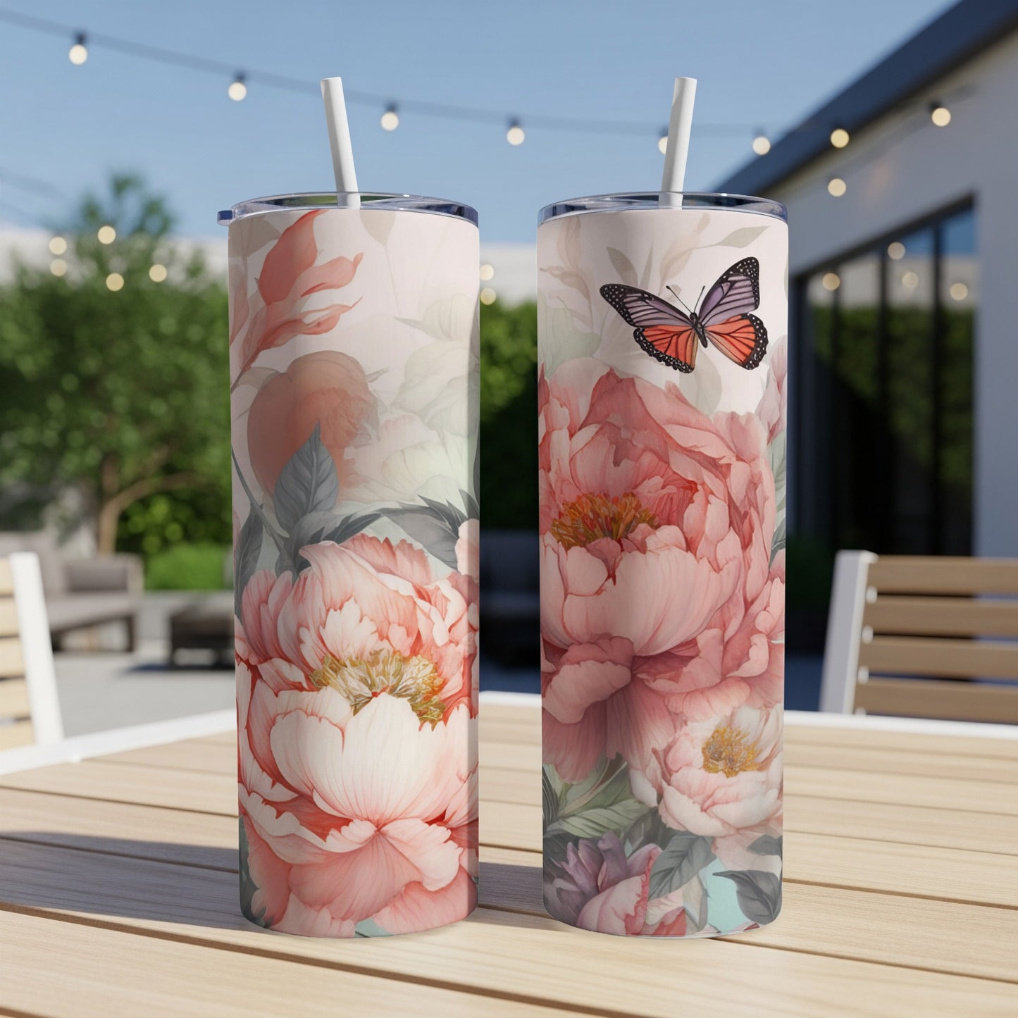 Two tall tumblers with floral and butterfly designs on a wooden table.