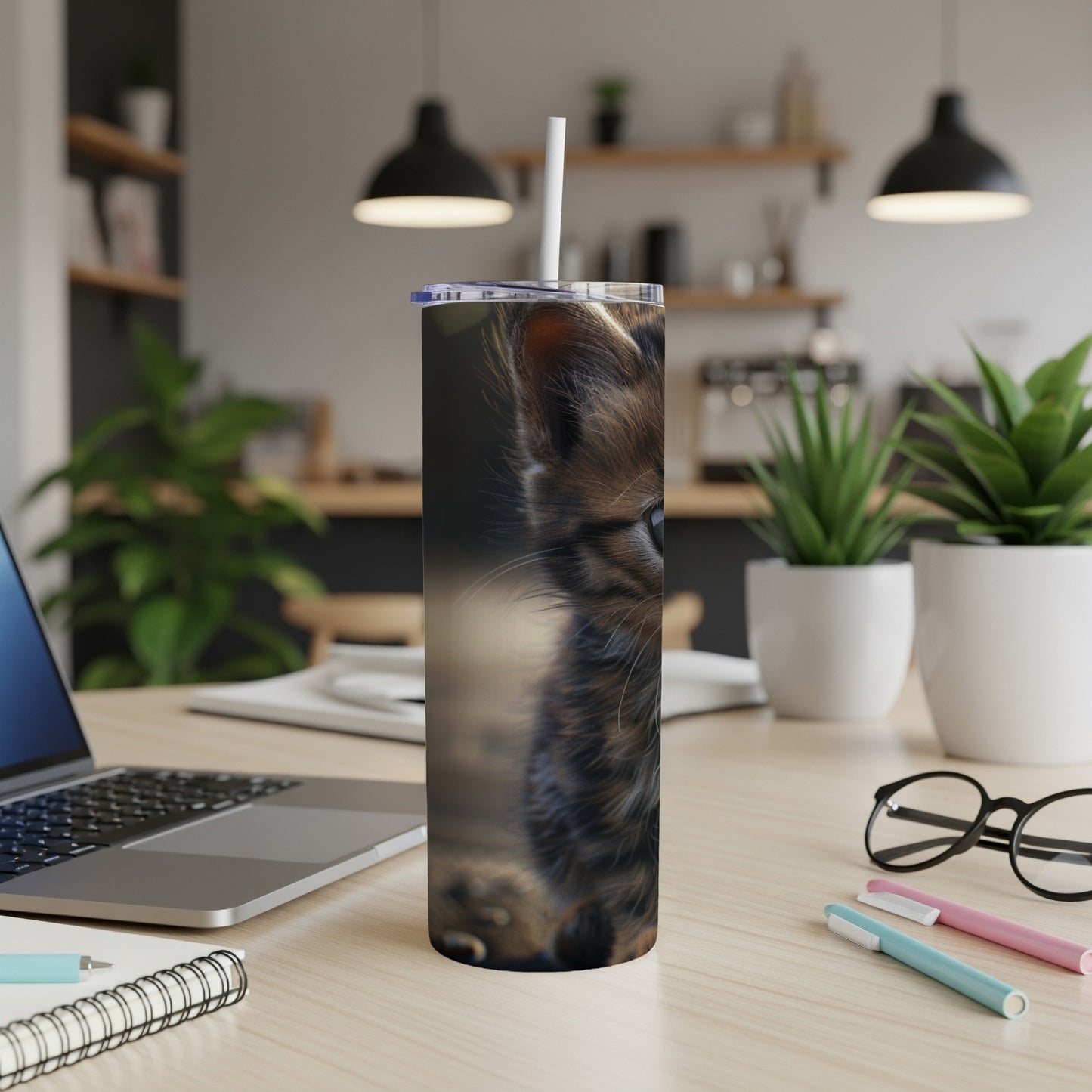 Close-up of a fluffy kitten's face on a stainless steel tumbler.
