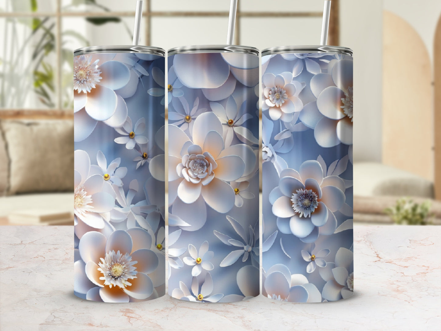 Three floral patterned tumblers with straws against a blurred background.