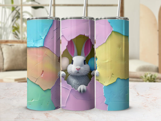 Easter bunny peeking from cracked eggshell on a pastel tumbler.